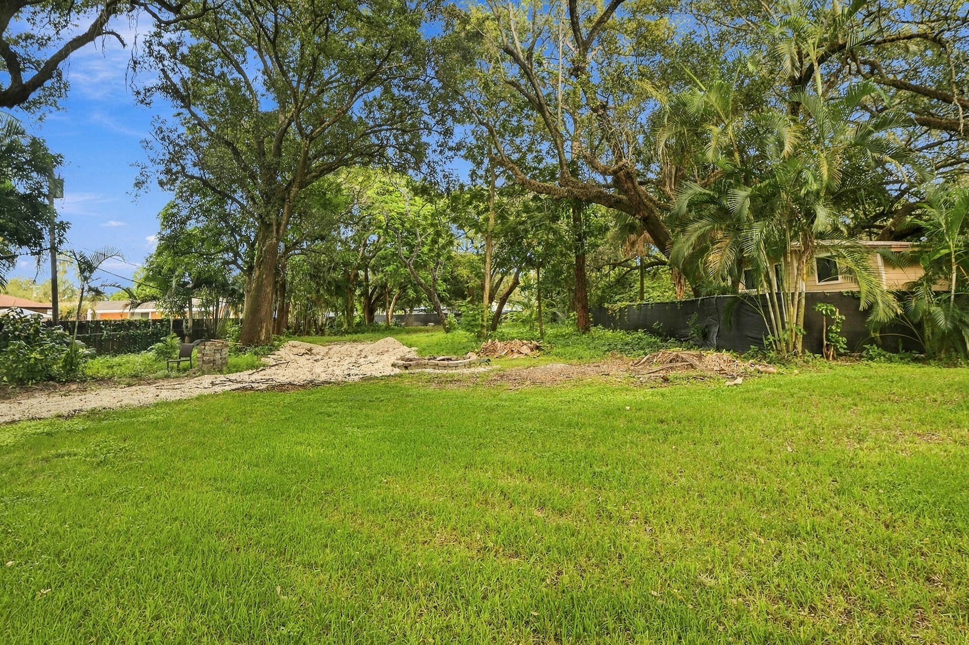 1549 SW 30th Place, Fort Lauderdale, FL 33315 Expansive grassy area featuring mature trees and a partial privacy wall