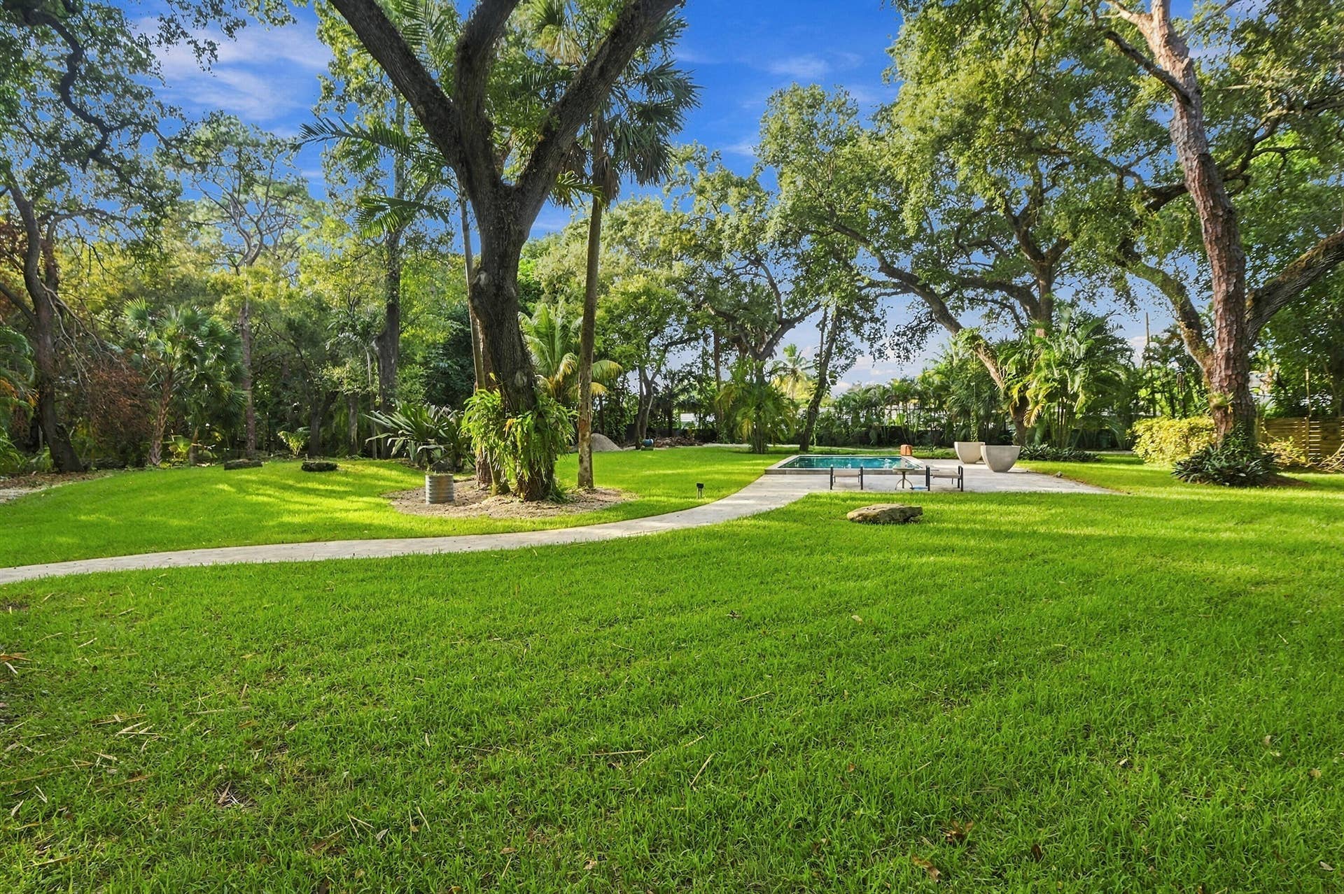 1549 SW 30th Place, Fort Lauderdale, FL 33315 Expansive green lawn with mature trees, a curvilinear paver pathway, and a rectangular swimming pool with an adjacent patio