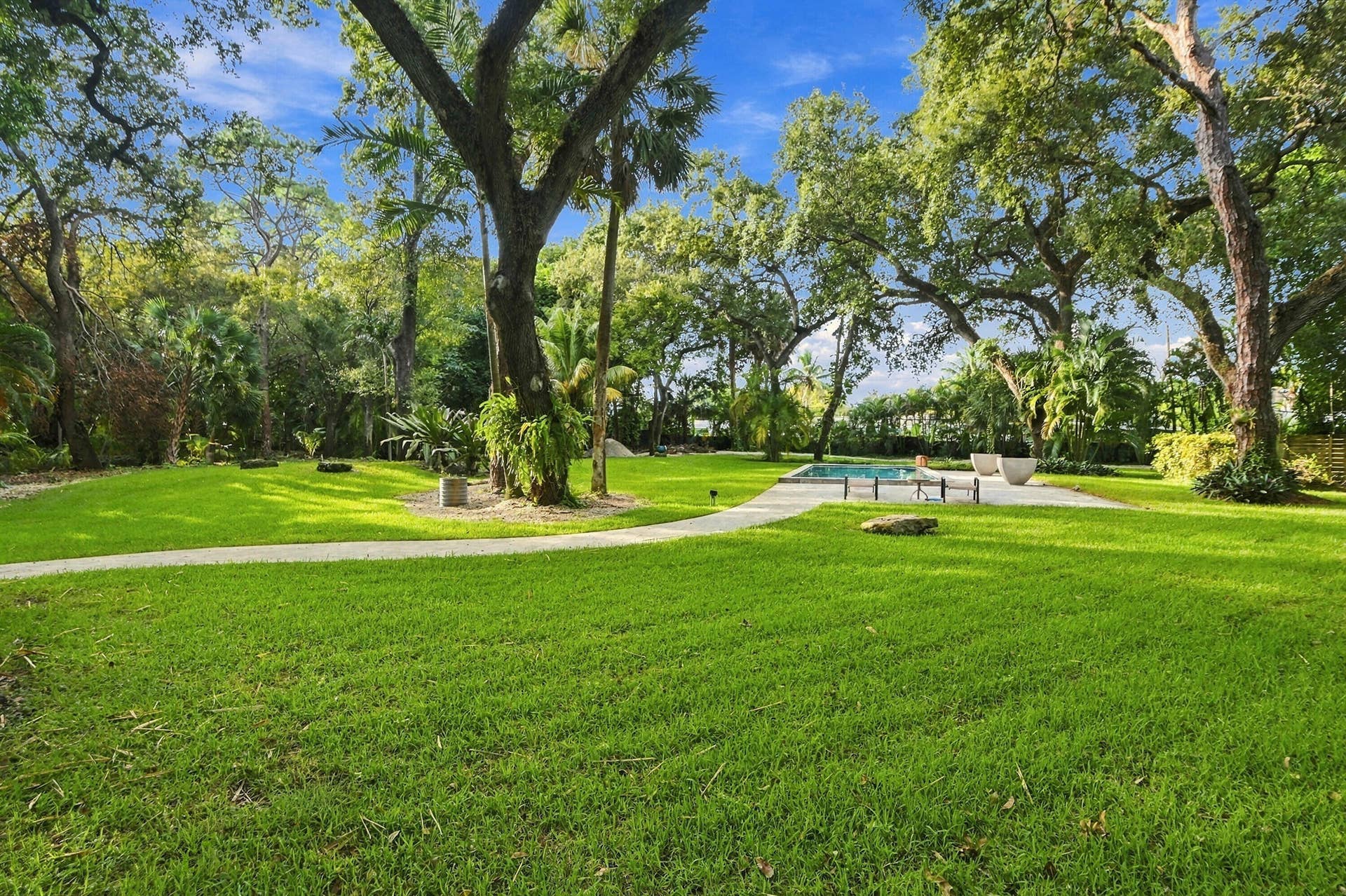 1549 SW 30th Place, Fort Lauderdale, FL 33315 Expansive lawn with mature trees, a swimming pool, and stone-finish paving