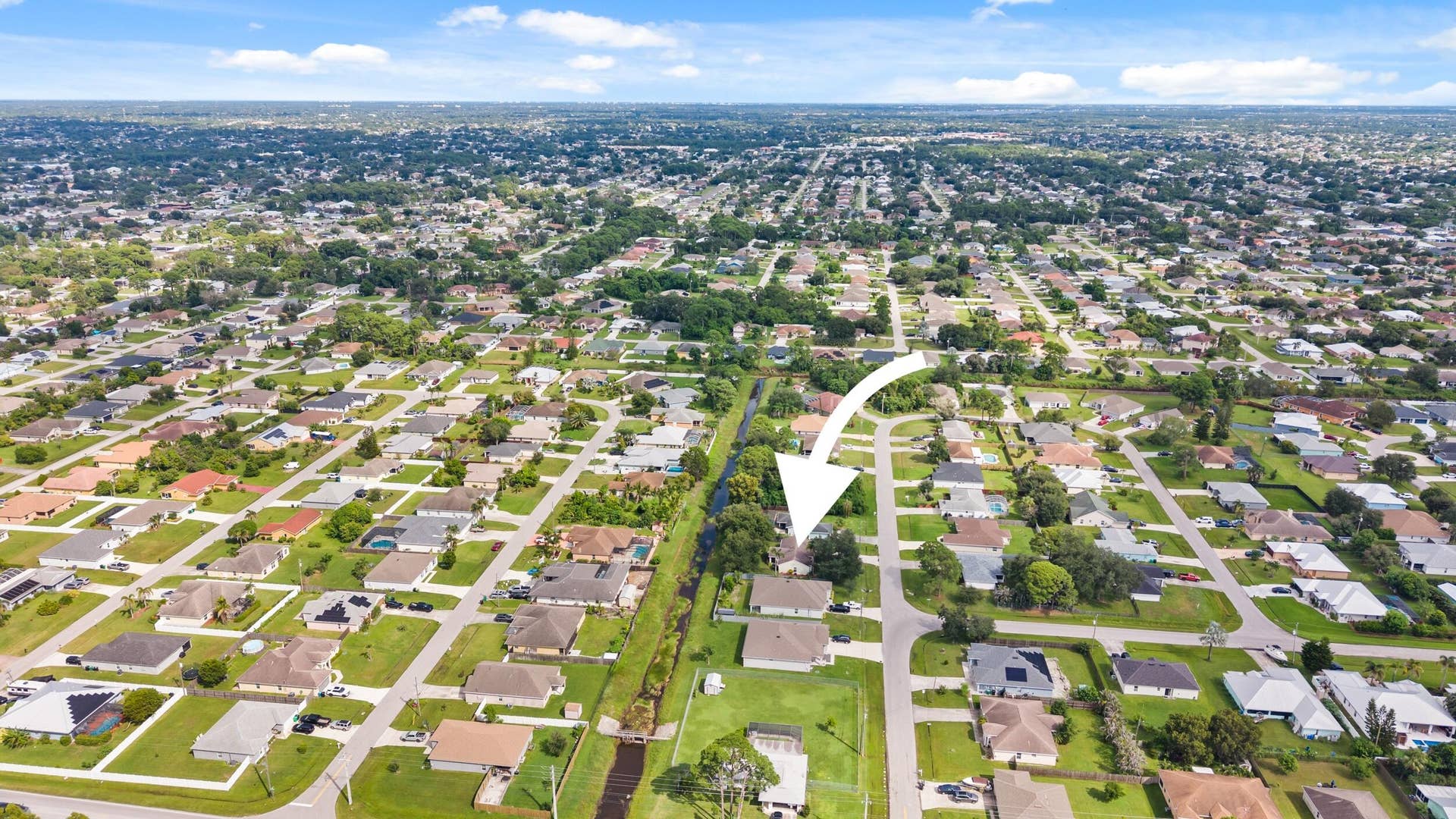 1649 SW ALVATON Avenue, Port St Lucie, FL 34953 Aerial perspective featuring a detached residential property situated on a corner lot with mature tree canopy and proximity to a canal