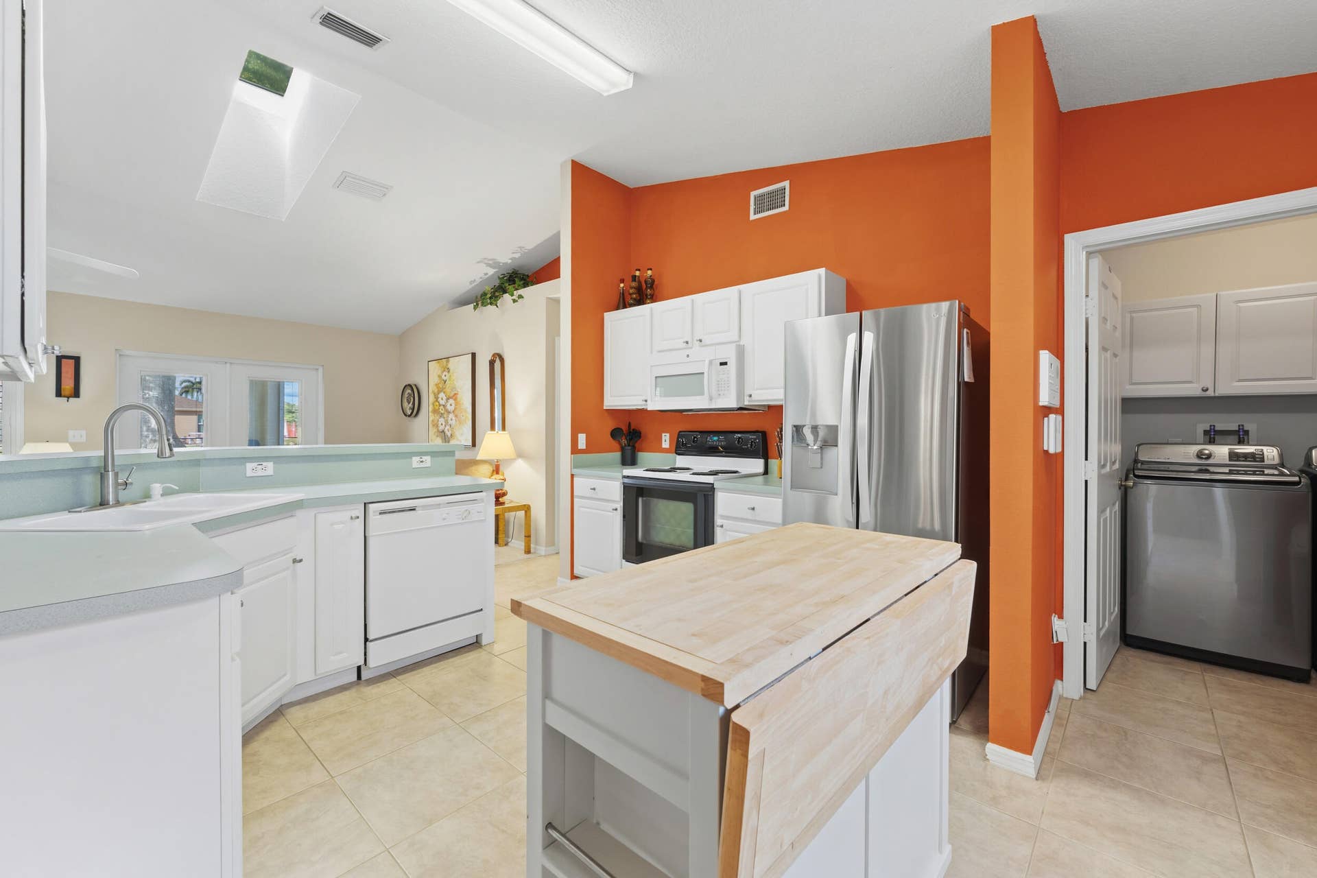 1649 SW ALVATON Avenue, Port St Lucie, FL 34953 Kitchen featuring white cabinetry, stainless steel appliances, butcher-block top center island, tile flooring, and a skylight