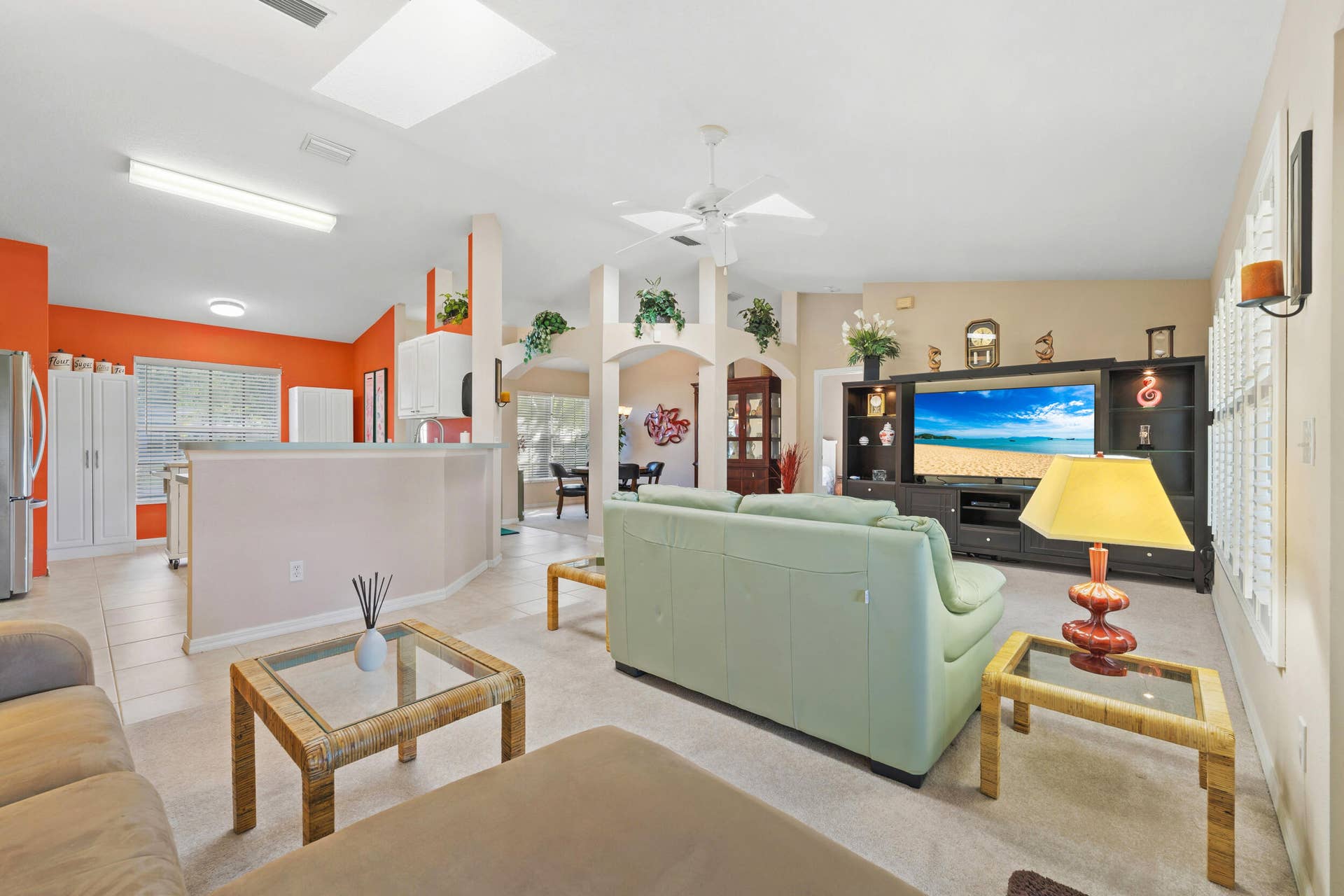 1649 SW ALVATON Avenue, Port St Lucie, FL 34953 Open-concept main living area featuring vaulted ceilings, built-in shelving, architectural archways, ceramic tile flooring, and a skylight