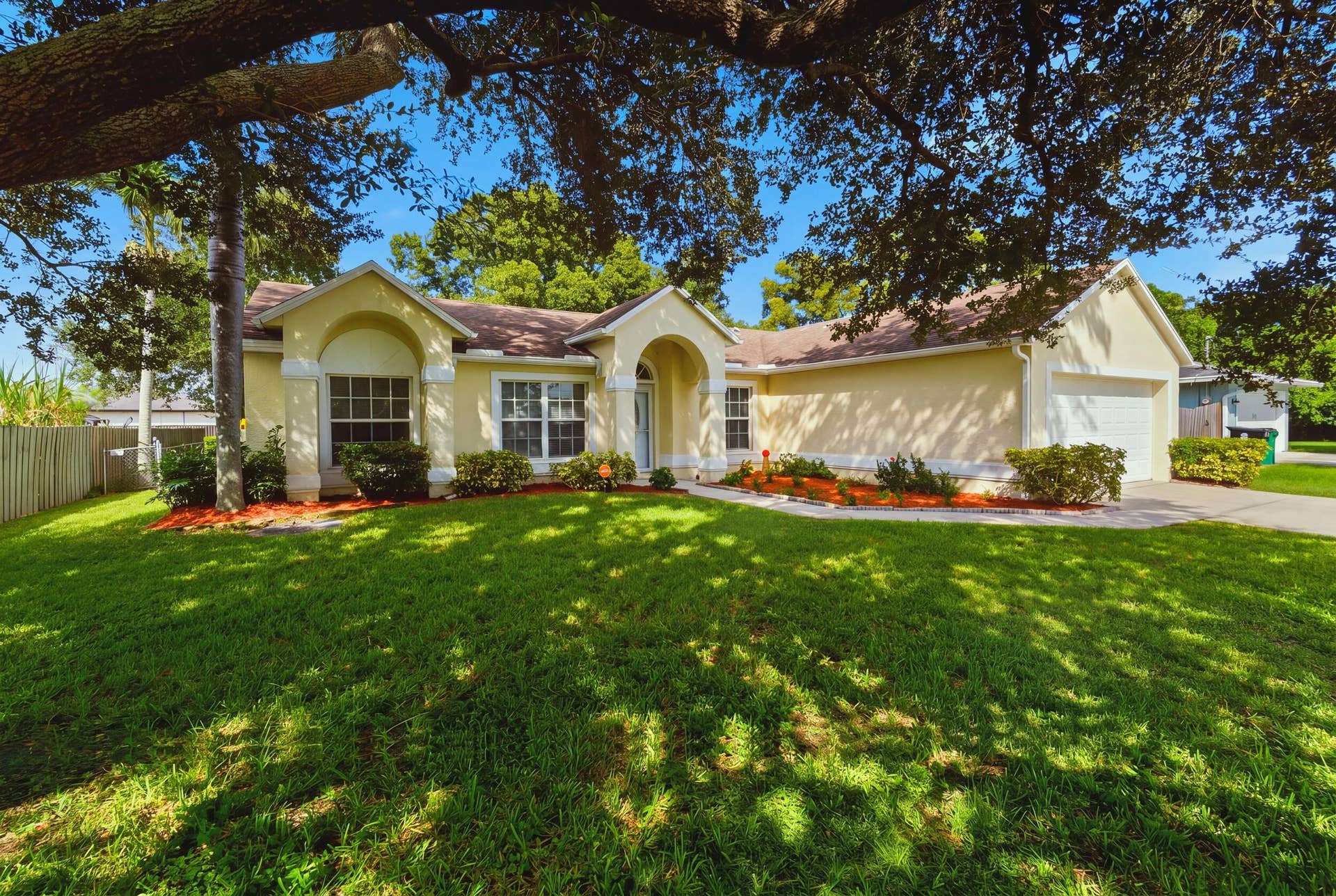 1649 SW ALVATON Avenue, Port St Lucie, FL 34953 Single-story residence featuring a stucco exterior, arched covered entryway, multi-pane windows, and an attached two-car garage