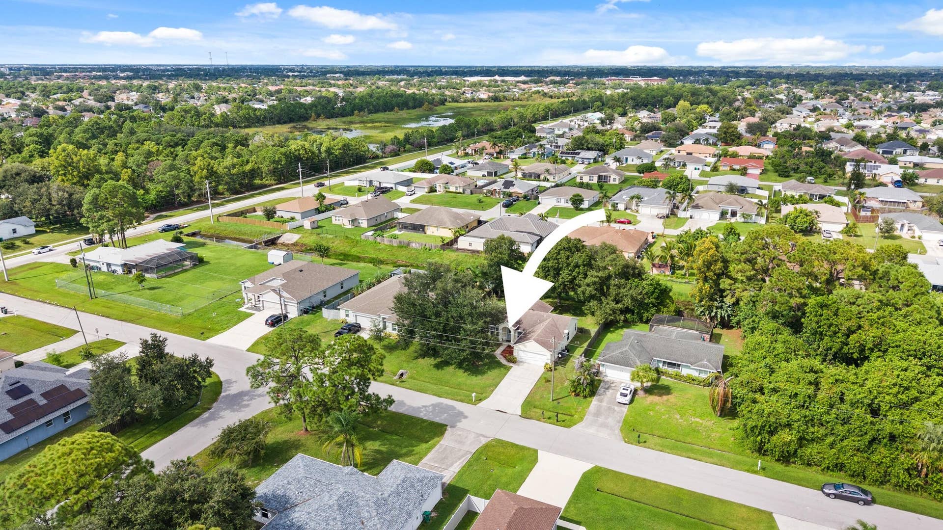 1649 SW ALVATON Avenue, Port St Lucie, FL 34953 Aerial perspective of a single-story residence featuring a concrete driveway, multi-gabled roofline, and established landscaping