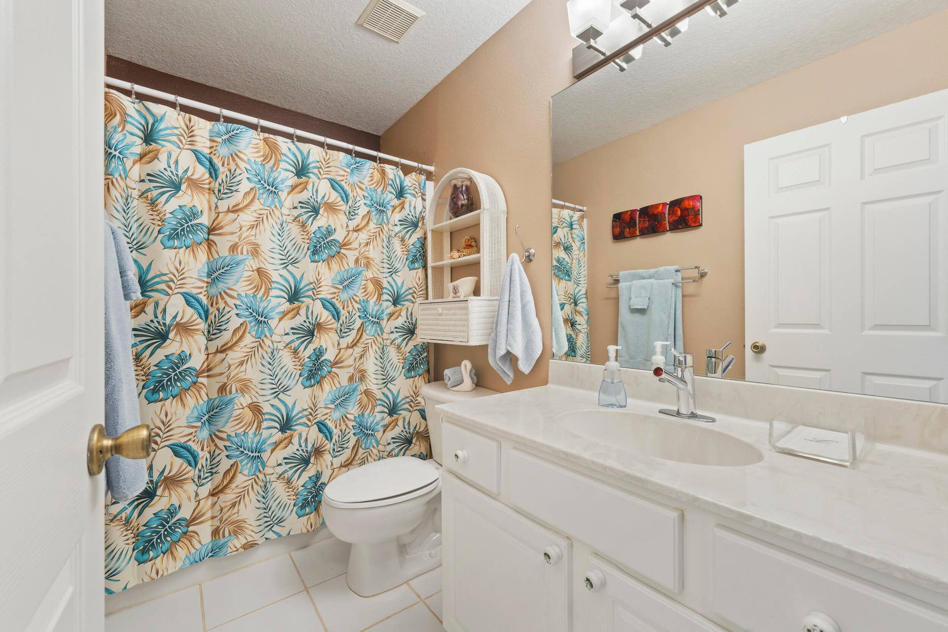 1649 SW ALVATON Avenue, Port St Lucie, FL 34953 Bathroom featuring a white vanity cabinet with a light-toned countertop, integrated oval sink, full-width wall mirror, and overhead multi-light fixture