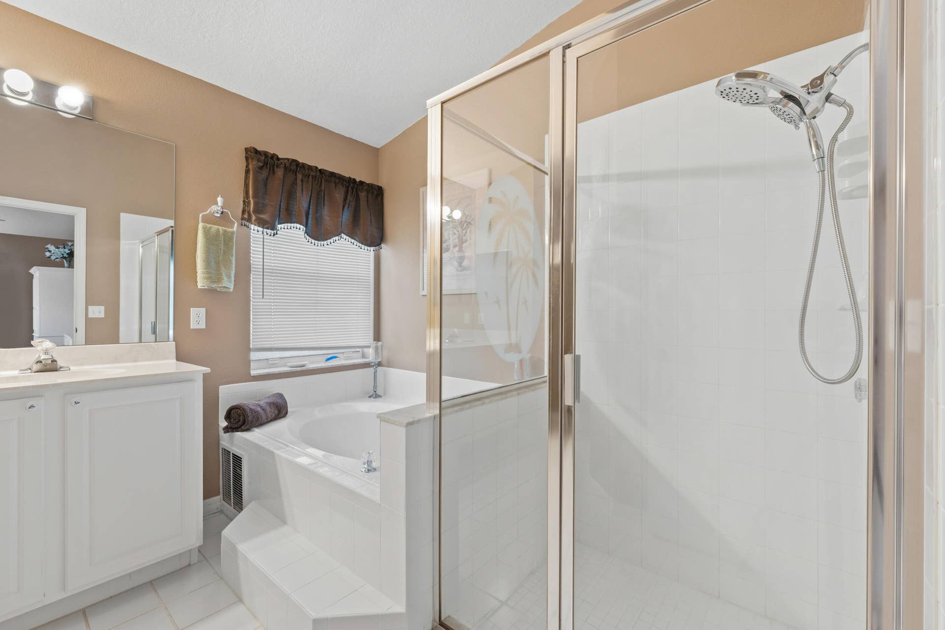 1649 SW ALVATON Avenue, Port St Lucie, FL 34953 Bathroom featuring a walk-in shower with a glass enclosure, a white soaking tub set in a tile surround, a vanity with white cabinetry, and wall-mounted light fixtures