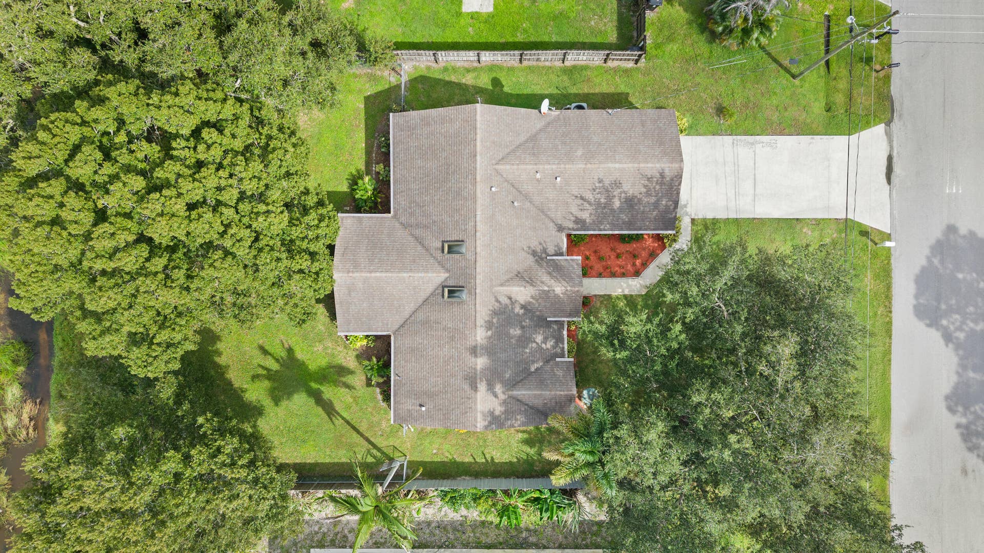 1649 SW ALVATON Avenue, Port St Lucie, FL 34953 Aerial perspective of residential property featuring an asphalt shingle roof, two skylights, concrete driveway, and expansive lot with mature trees