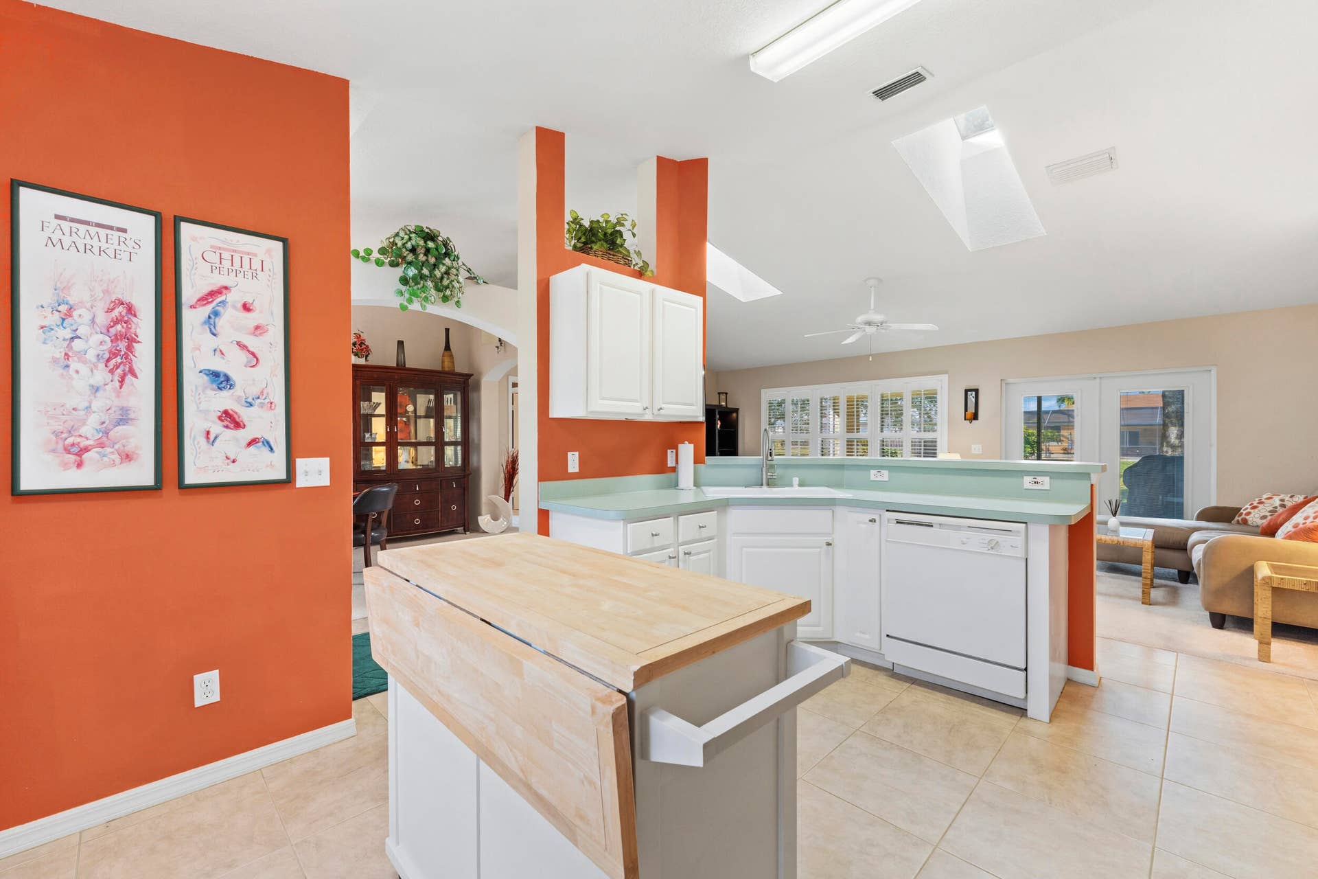 1649 SW ALVATON Avenue, Port St Lucie, FL 34953 Kitchen featuring a portable wood-top island, white cabinetry, solid-surface countertops, tile flooring, and vaulted ceilings with skylights