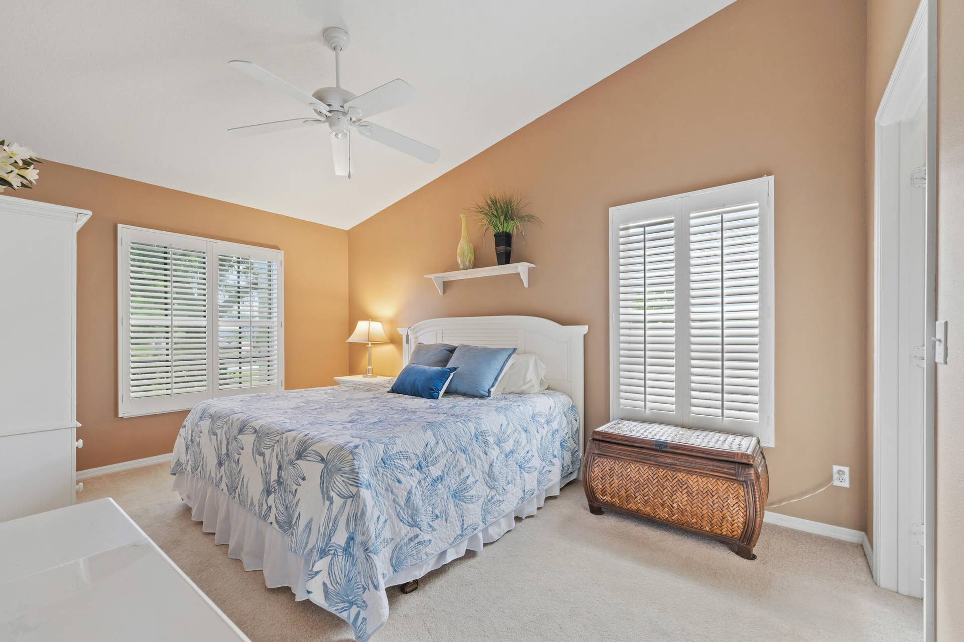 1649 SW ALVATON Avenue, Port St Lucie, FL 34953 Vaulted ceiling featuring a ceiling fan, dual windows with plantation shutters, and a wall-mounted floating display shelf