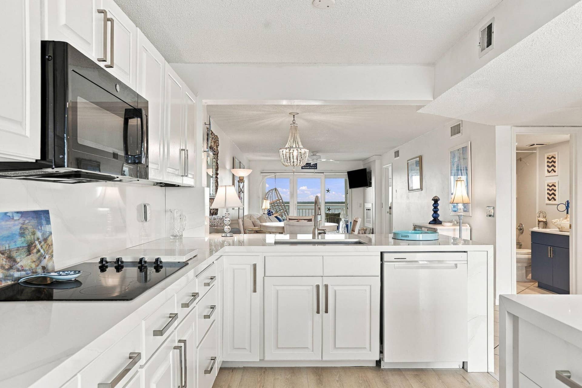White cabinetry with bar pull hardware, integrated cooktop, built-in microwave, and wood-finish flooring