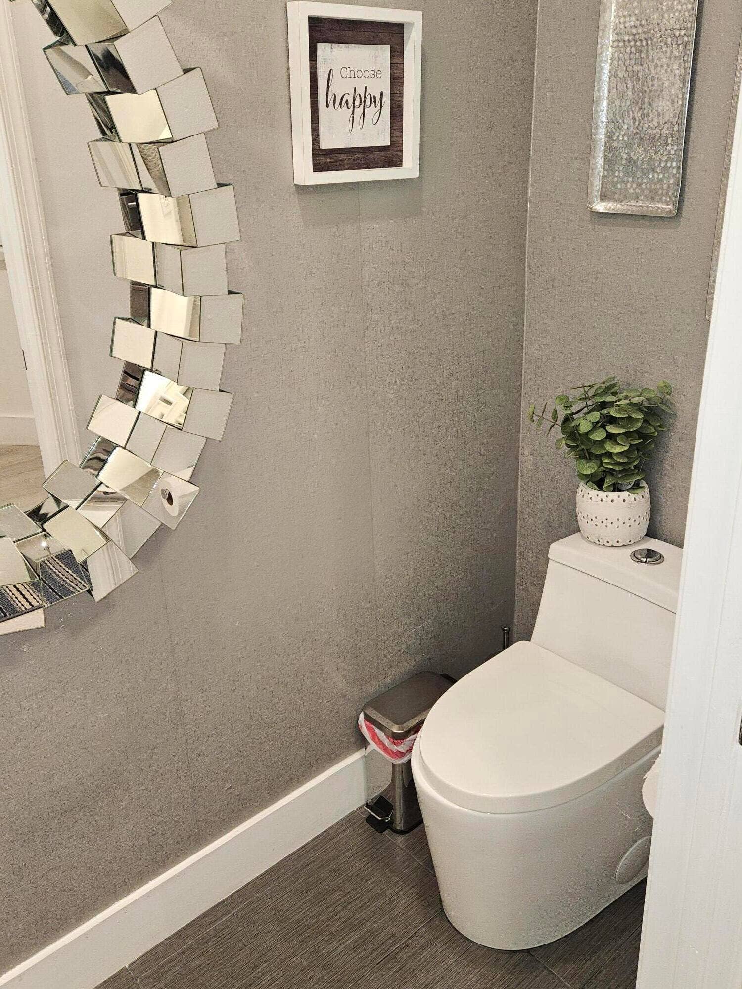 1460 SW 47TH Avenue, #1460, Deerfield Beach, Deerfield Beach, FL 33442 Powder room featuring a modern white ceramic toilet, dark wood-finish flooring, neutral textured wall treatment, framed wall dcor, and decorative potted greenery