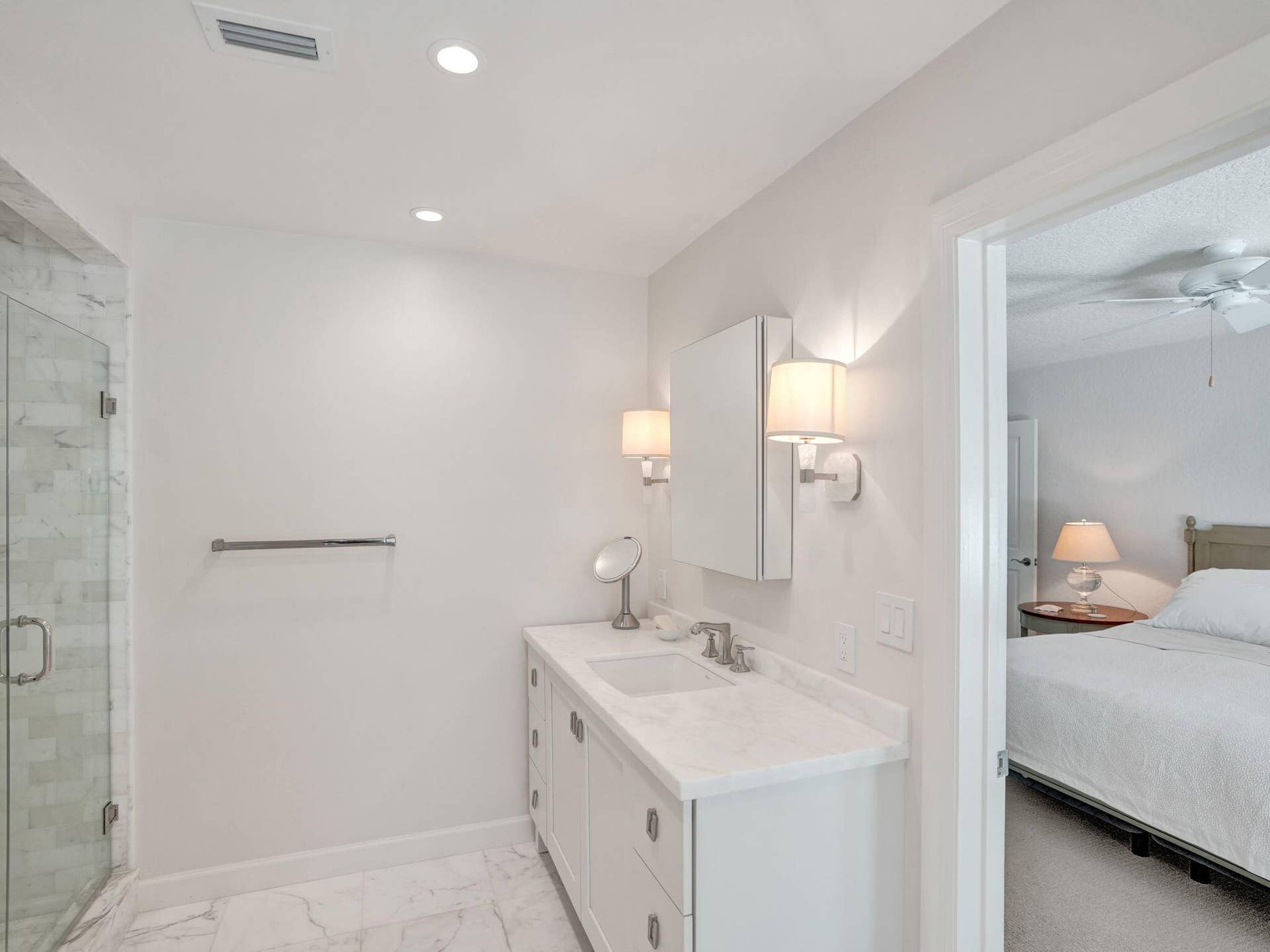 Bathroom featuring a white vanity with an undermount sink, a stone-finish countertop, and wall-mounted sconce lighting