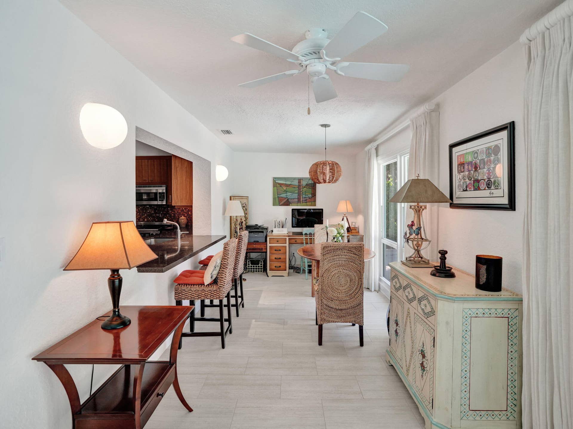 Open concept living area with light-toned flooring, an integrated breakfast bar, and a ceiling fan