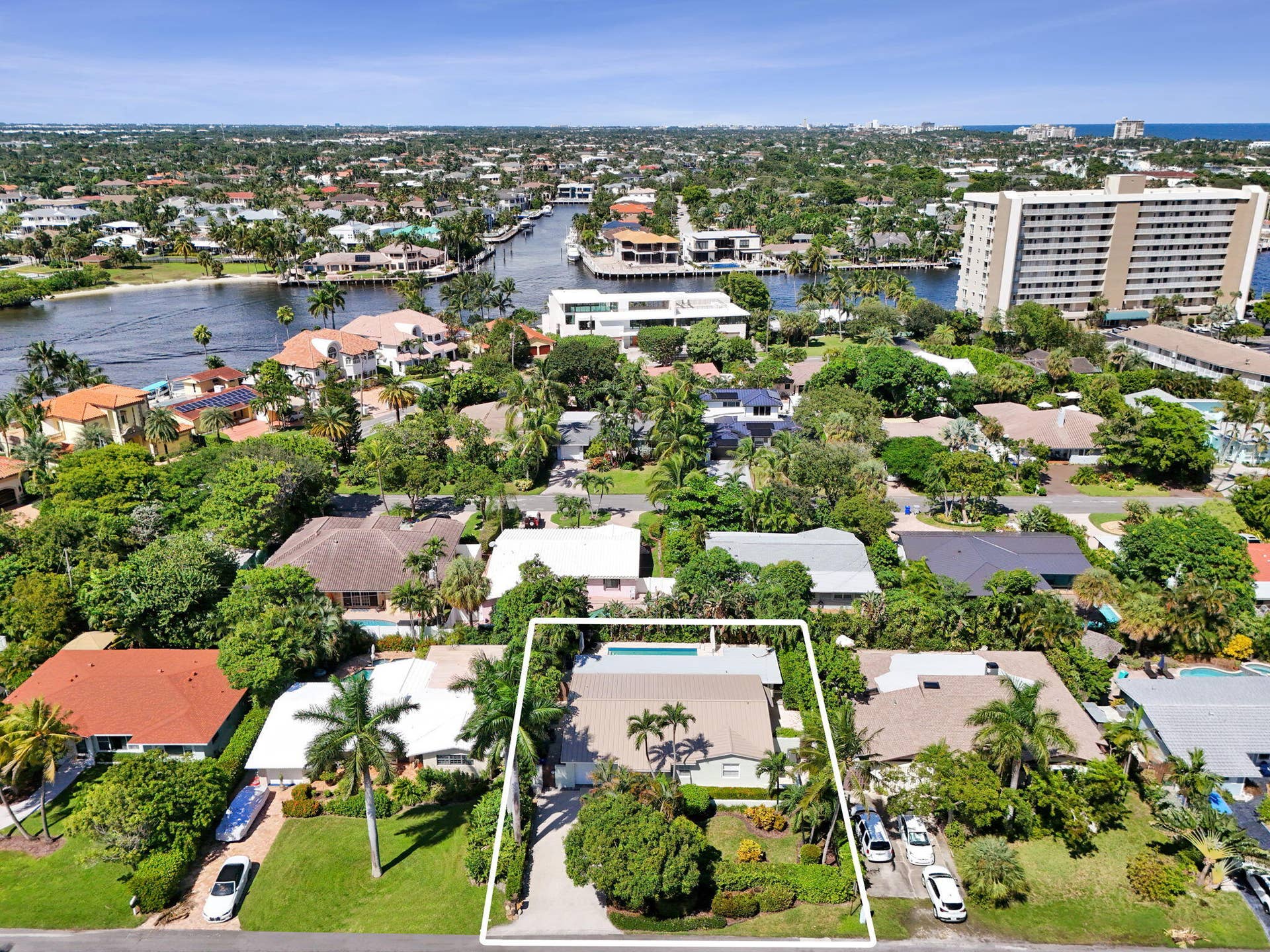 Aerial perspective featuring a residential street, a maturely landscaped property, and swimming pool