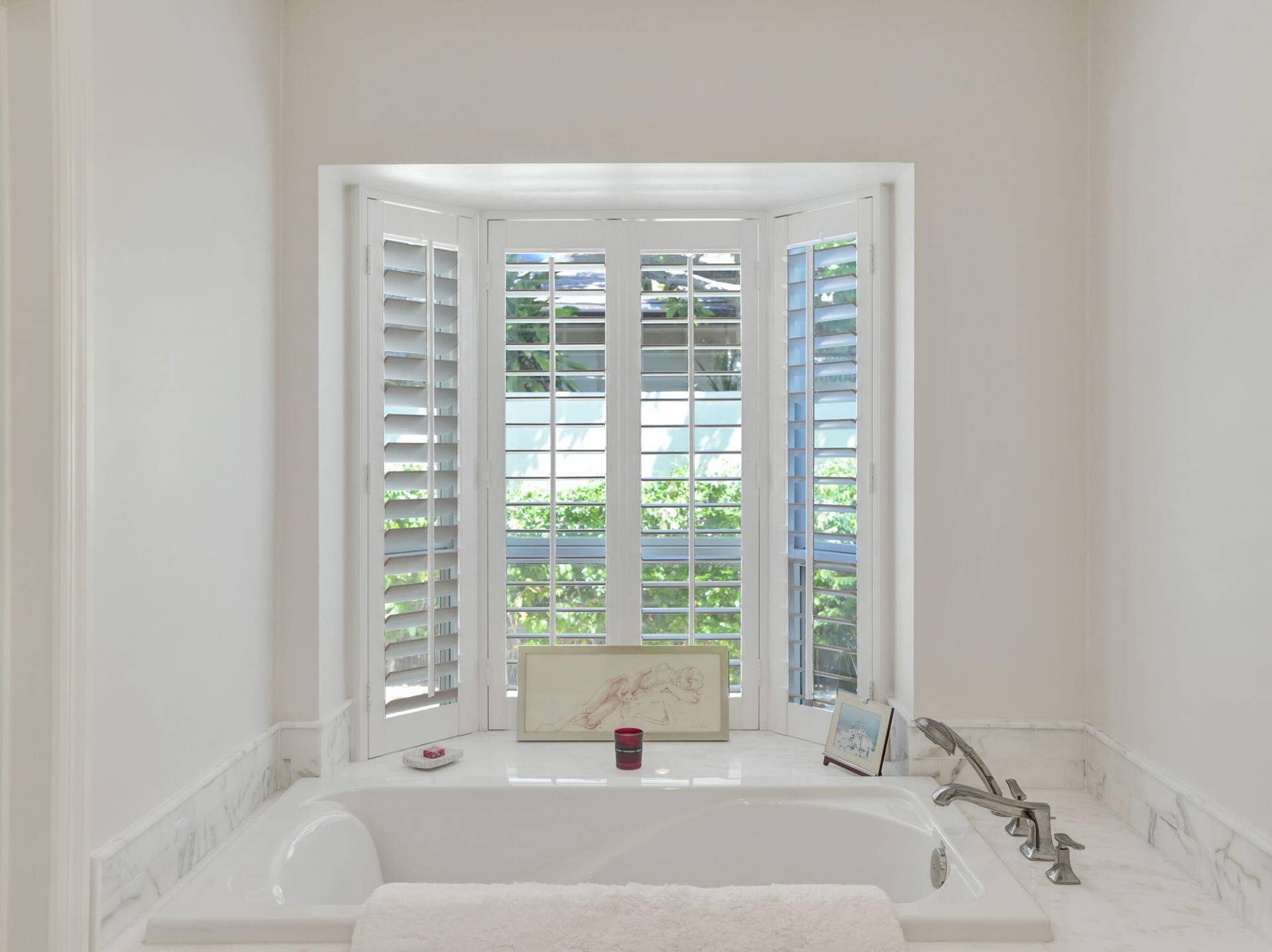 Soaking tub with a polished deck-mounted faucet and handheld shower sprayer, surrounded by a marble-patterned countertop