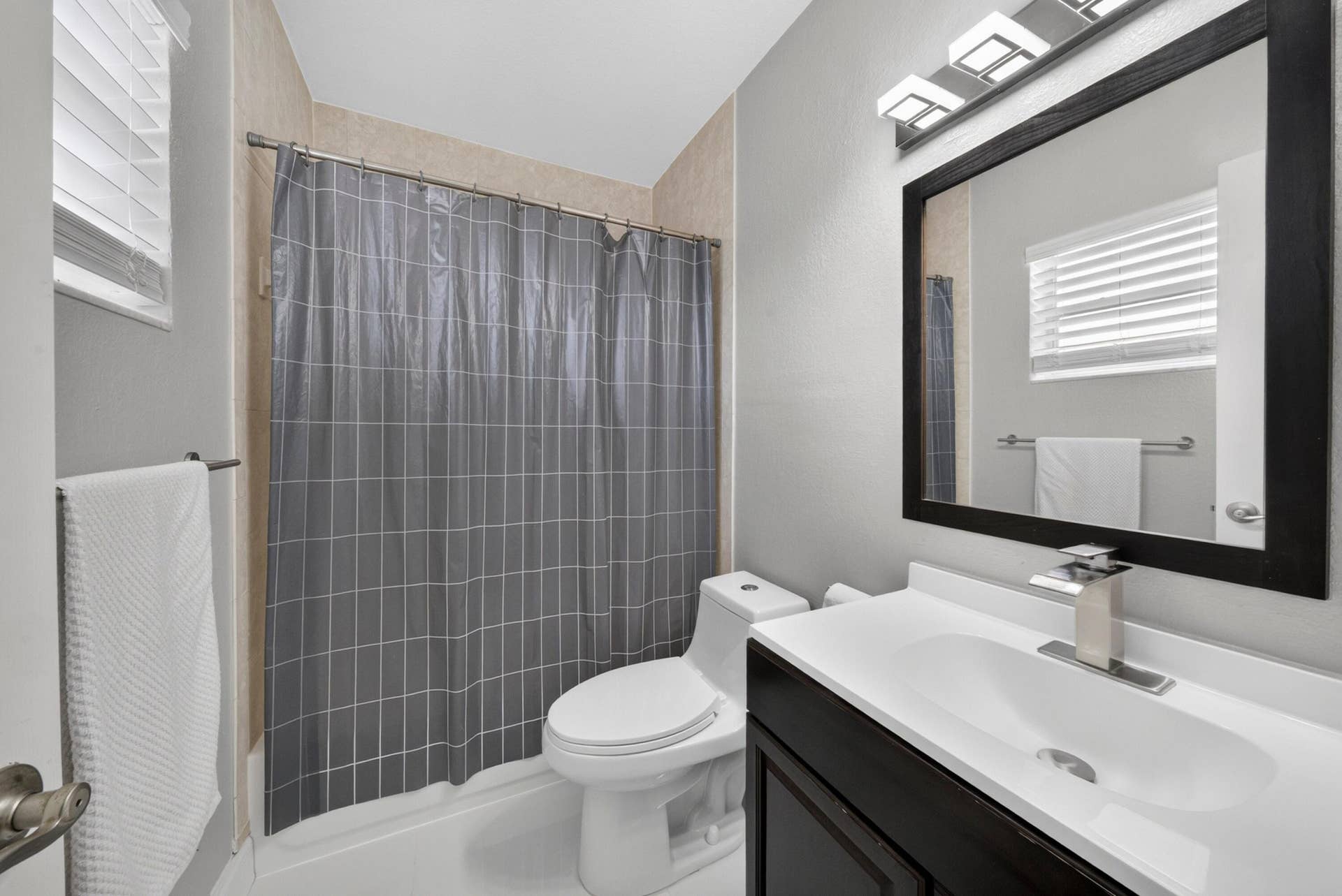 744 NE 14th Avenue, #21, Fort Lauderdale, FL 33304 Bathroom featuring a vanity with a white countertop and rectangular sink, a framed wall mirror, and a tub/shower combination with tiled surround