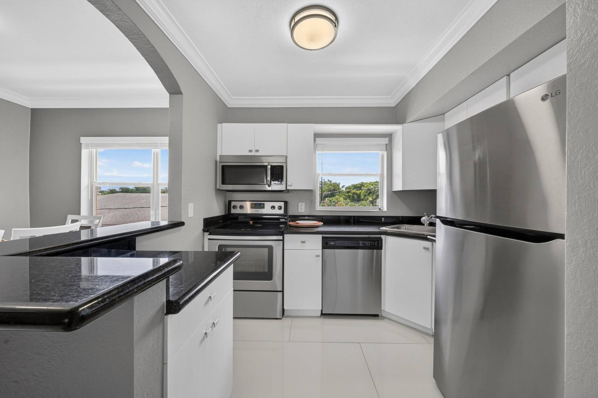 744 NE 14th Avenue, #21, Fort Lauderdale, FL 33304 Kitchen featuring stainless steel appliances, dark stone countertops, white cabinetry, and tile flooring