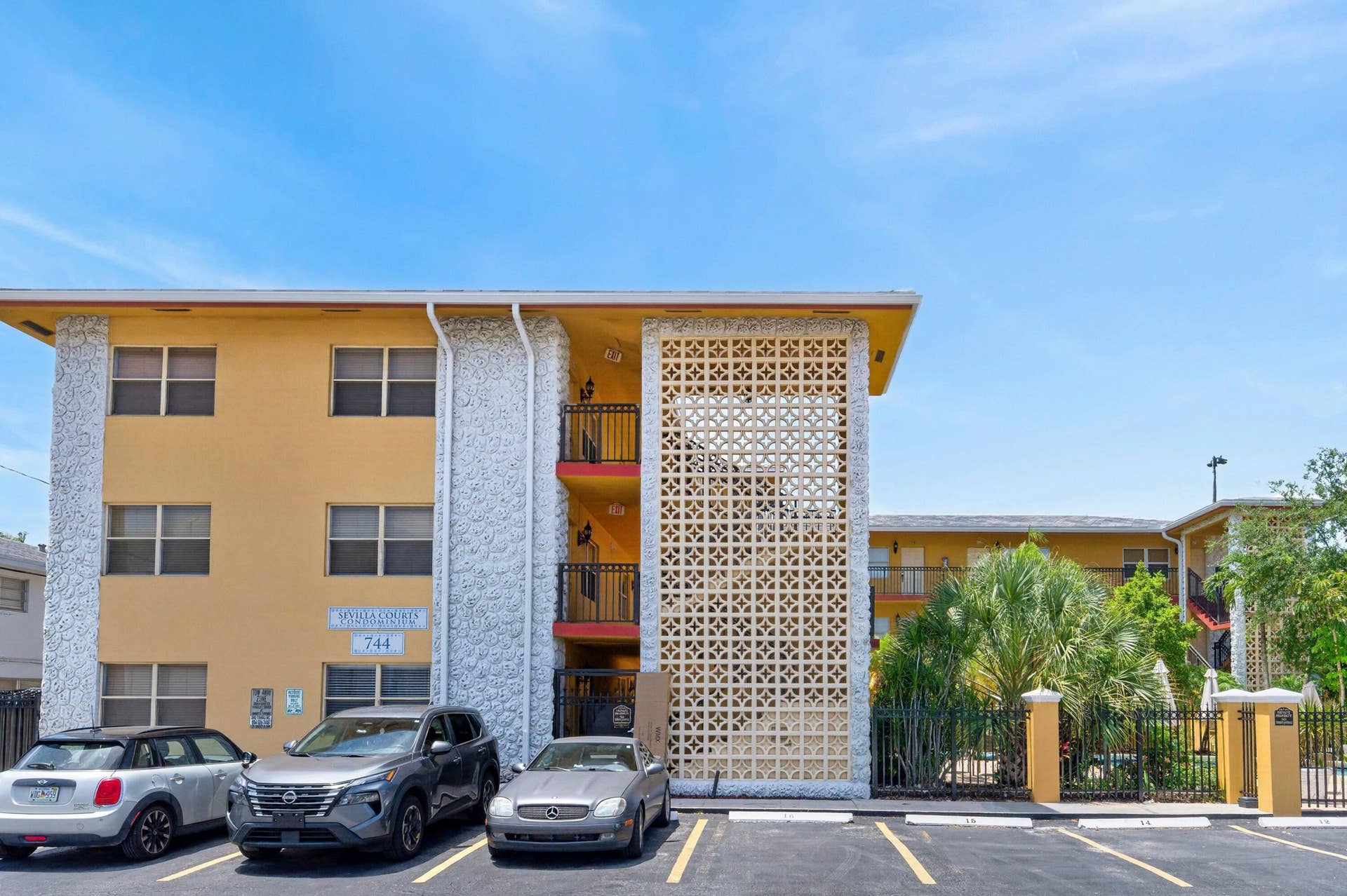 744 NE 14th Avenue, #21, Fort Lauderdale, FL 33304 Multi-story building with a yellow exterior finish, textured white architectural elements, and black metal balcony railings