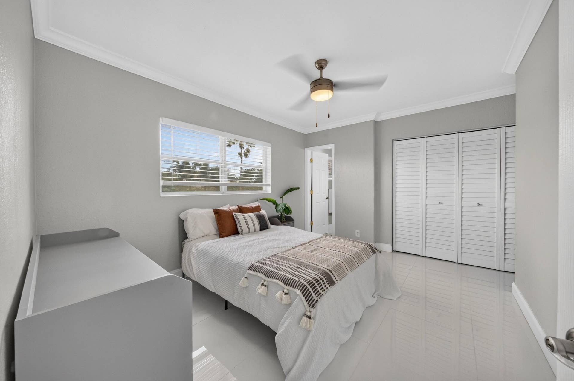 744 NE 14th Avenue, #21, Fort Lauderdale, FL 33304 Crisp crown molding, ceiling fan with integrated lighting, window with horizontal blinds, and louvered bifold closet doors