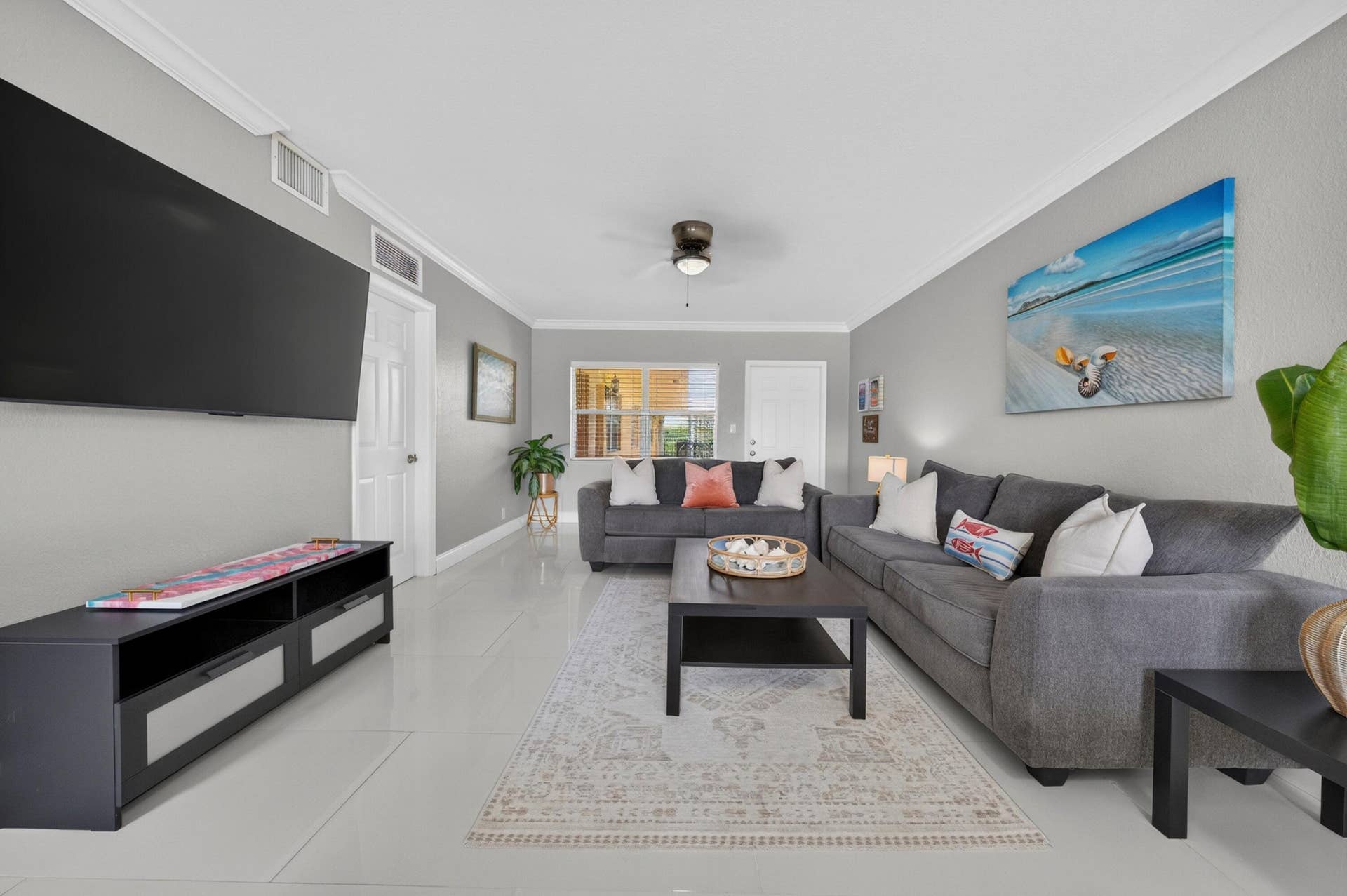 744 NE 14th Avenue, #21, Fort Lauderdale, FL 33304 Spacious living area featuring light gray wall tones, crown molding, a ceiling fan, and tile flooring throughout