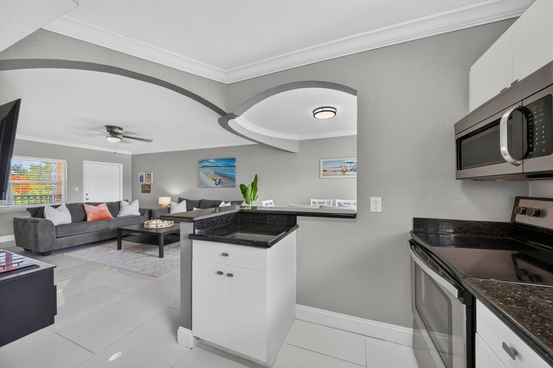 744 NE 14th Avenue, #21, Fort Lauderdale, FL 33304 Arched architectural details, white cabinetry, stainless steel appliances, black countertops, and light tile flooring
