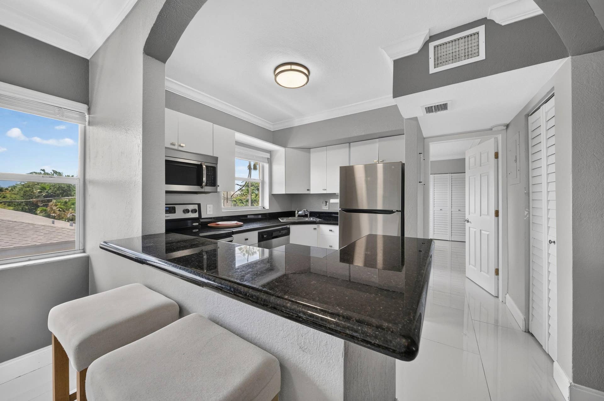 744 NE 14th Avenue, #21, Fort Lauderdale, FL 33304 Kitchen featuring stainless steel appliances, white cabinetry, dark stone countertops, and white tile flooring