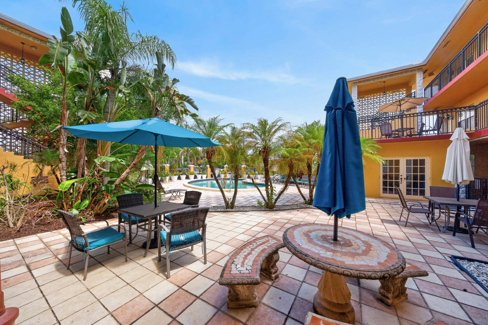 744 NE 14th Avenue, #21, Fort Lauderdale, FL 33304 Expansive outdoor patio with patterned tile flooring, surrounded by lush tropical landscaping and mature palm trees