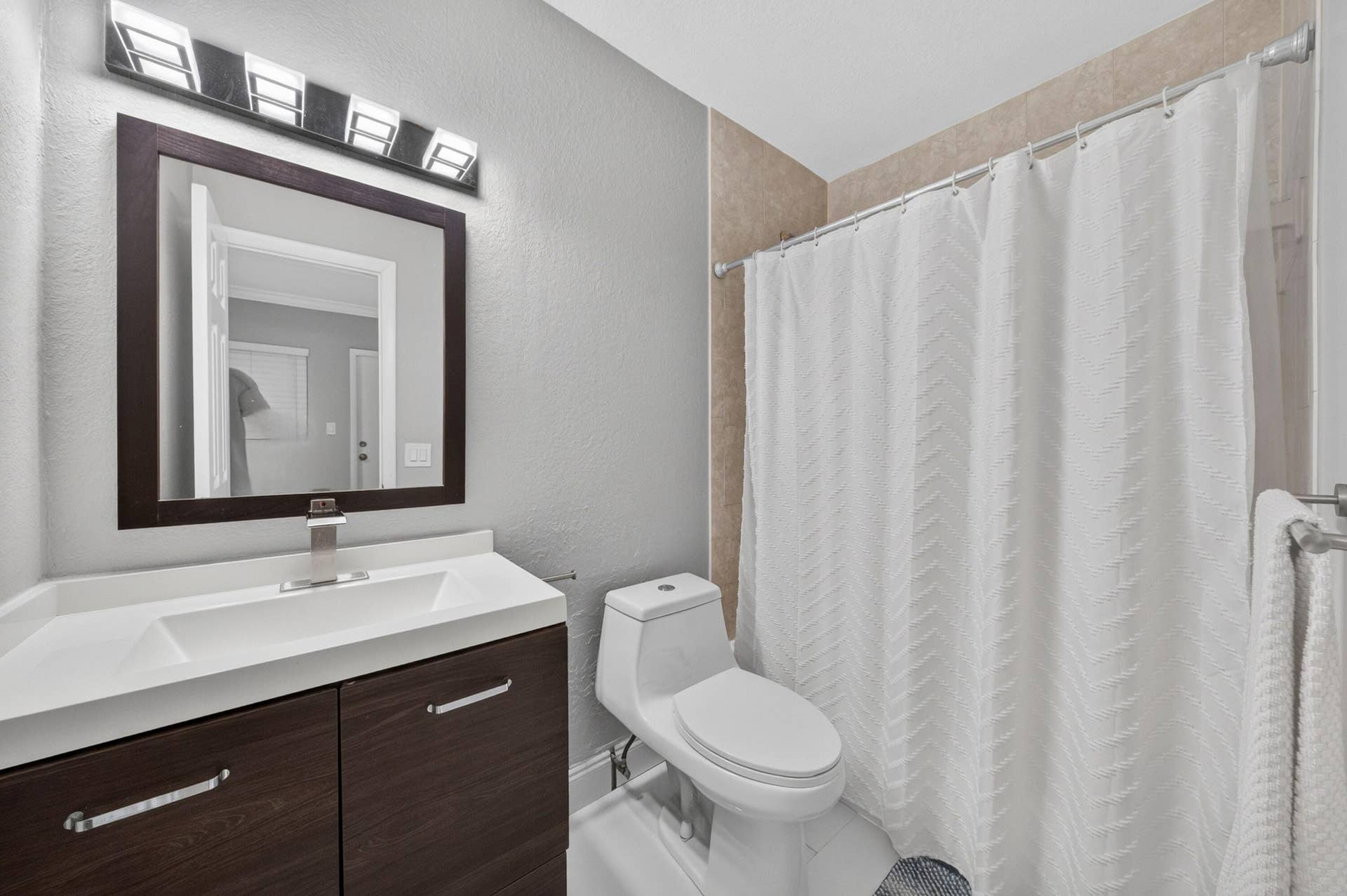 744 NE 14th Avenue, #21, Fort Lauderdale, FL 33304 Contemporary vanity with a dark wood-finish cabinet and integrated white sink