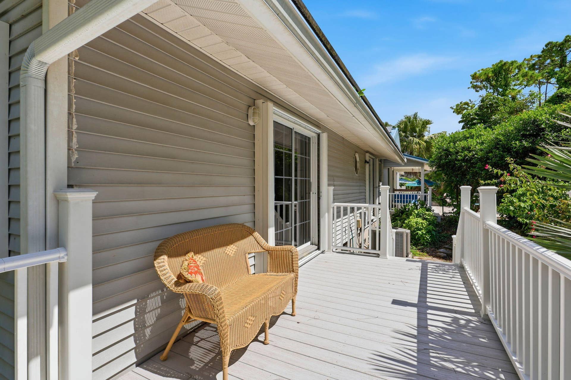 Exterior siding with white trim, white rain gutter, and a light-colored wood-finish deck