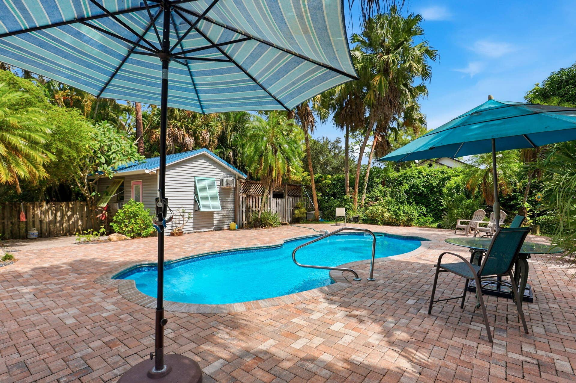 In-ground swimming pool with handrails, surrounded by a paver patio