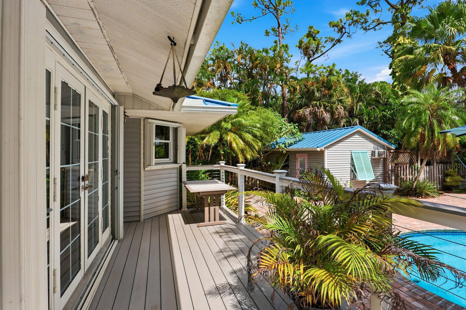 Spacious deck with French doors, white railing, and an adjacent swimming pool