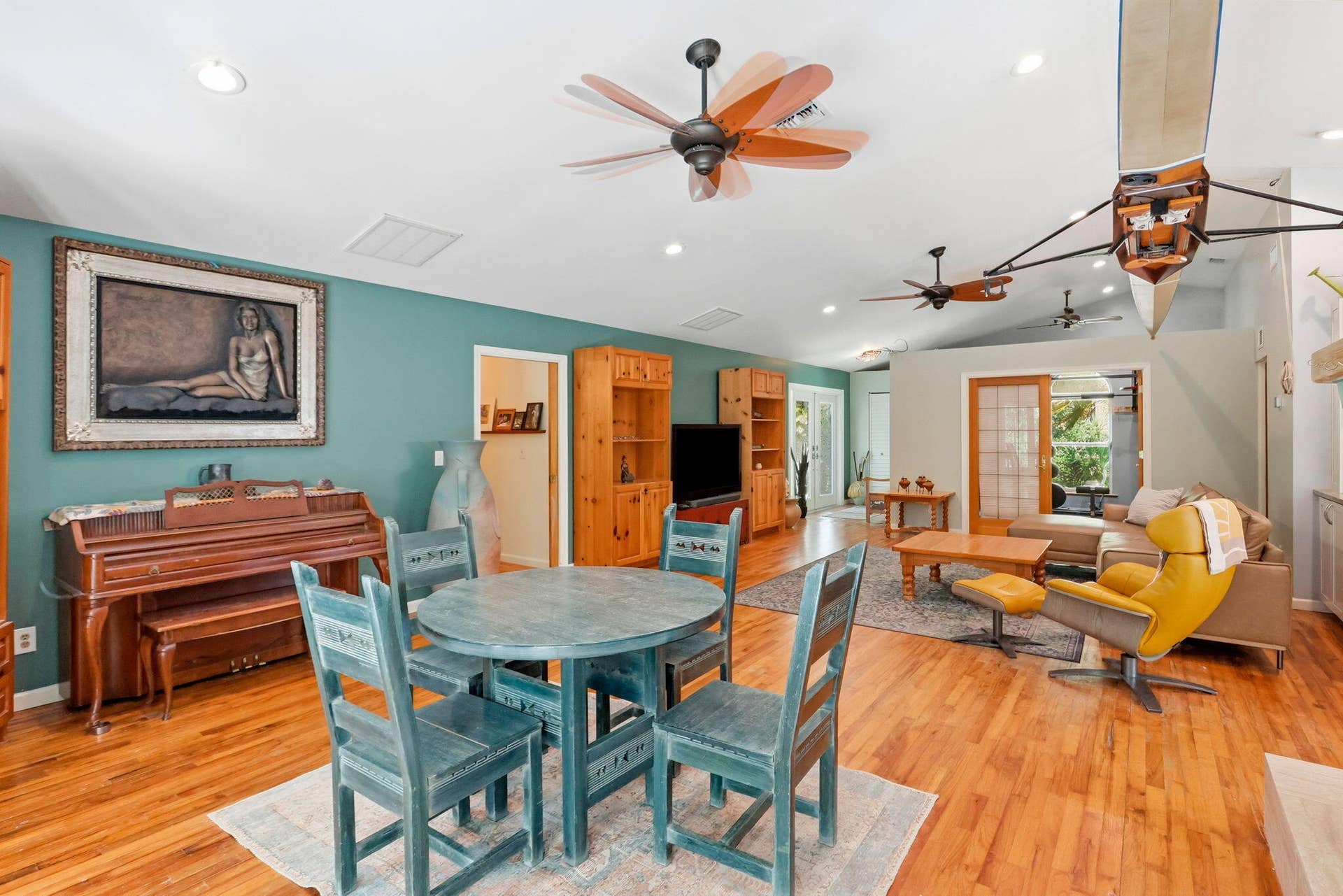Vaulted ceiling with recessed lighting, wood-finish flooring, ceiling fans, built-in shelving, and sliding glass door access to the exterior
