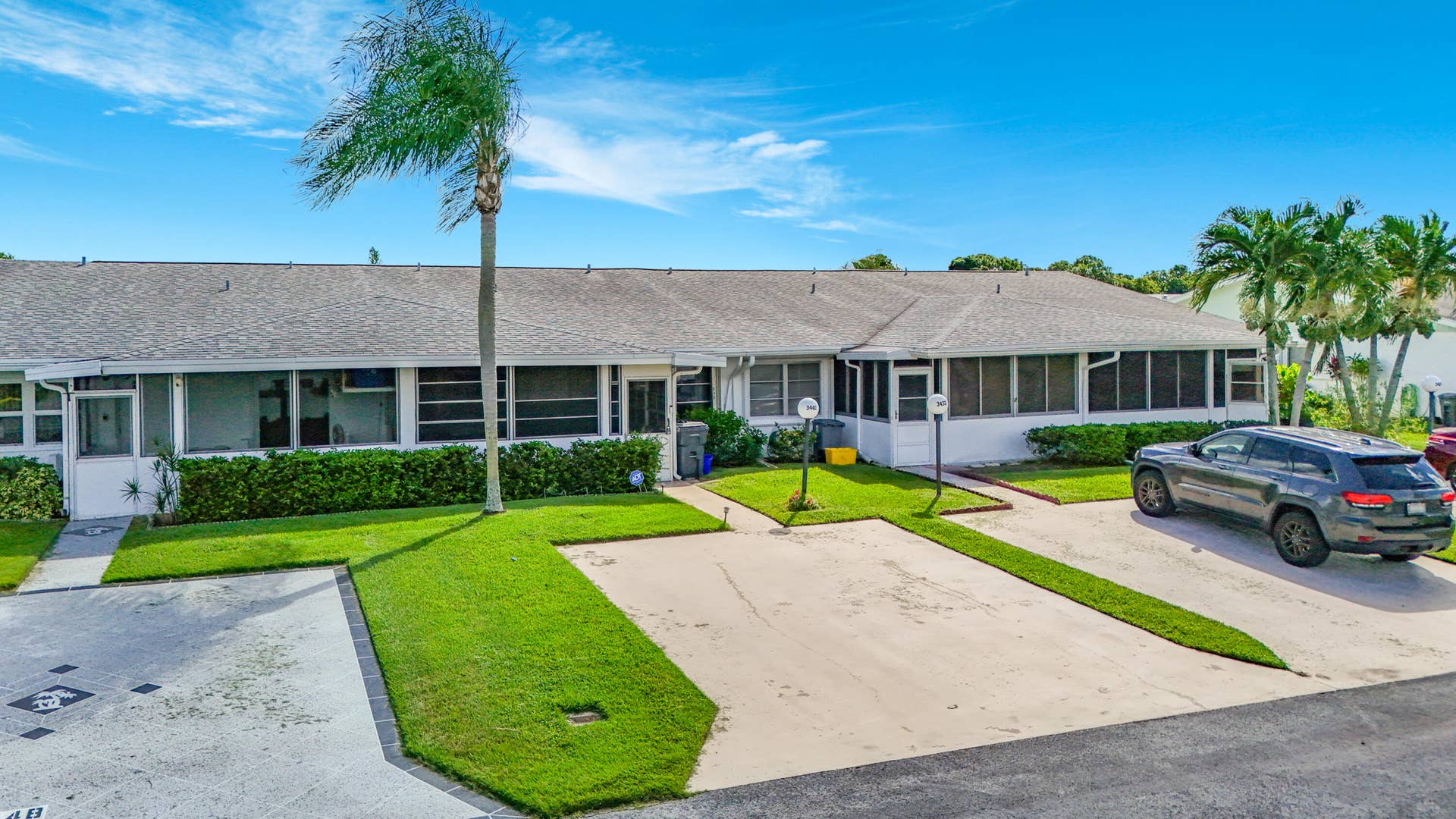 Single-story residential building with a grey shingle roof, white exterior walls, and multiple screened-in patio areas