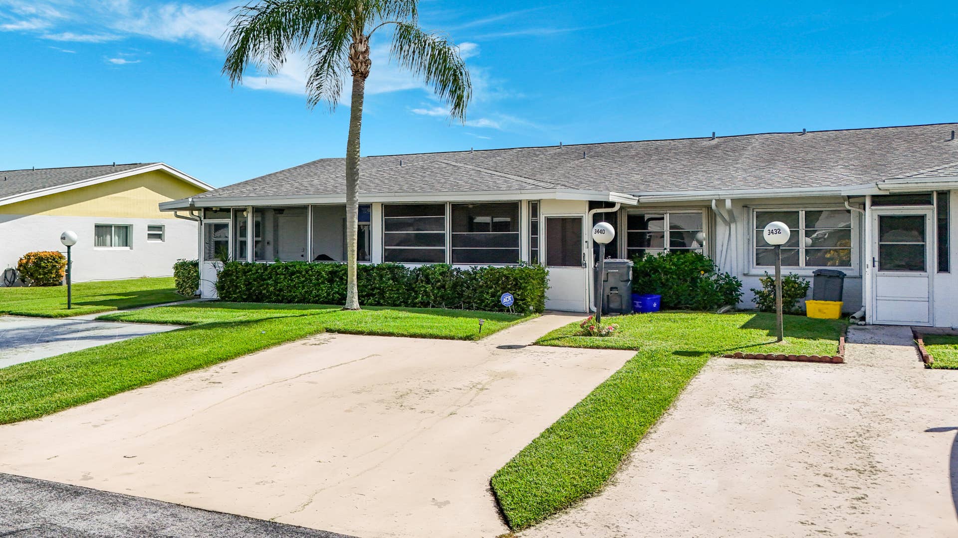 Front exterior featuring a screened porch, multiple parking spaces, and manicured landscaping