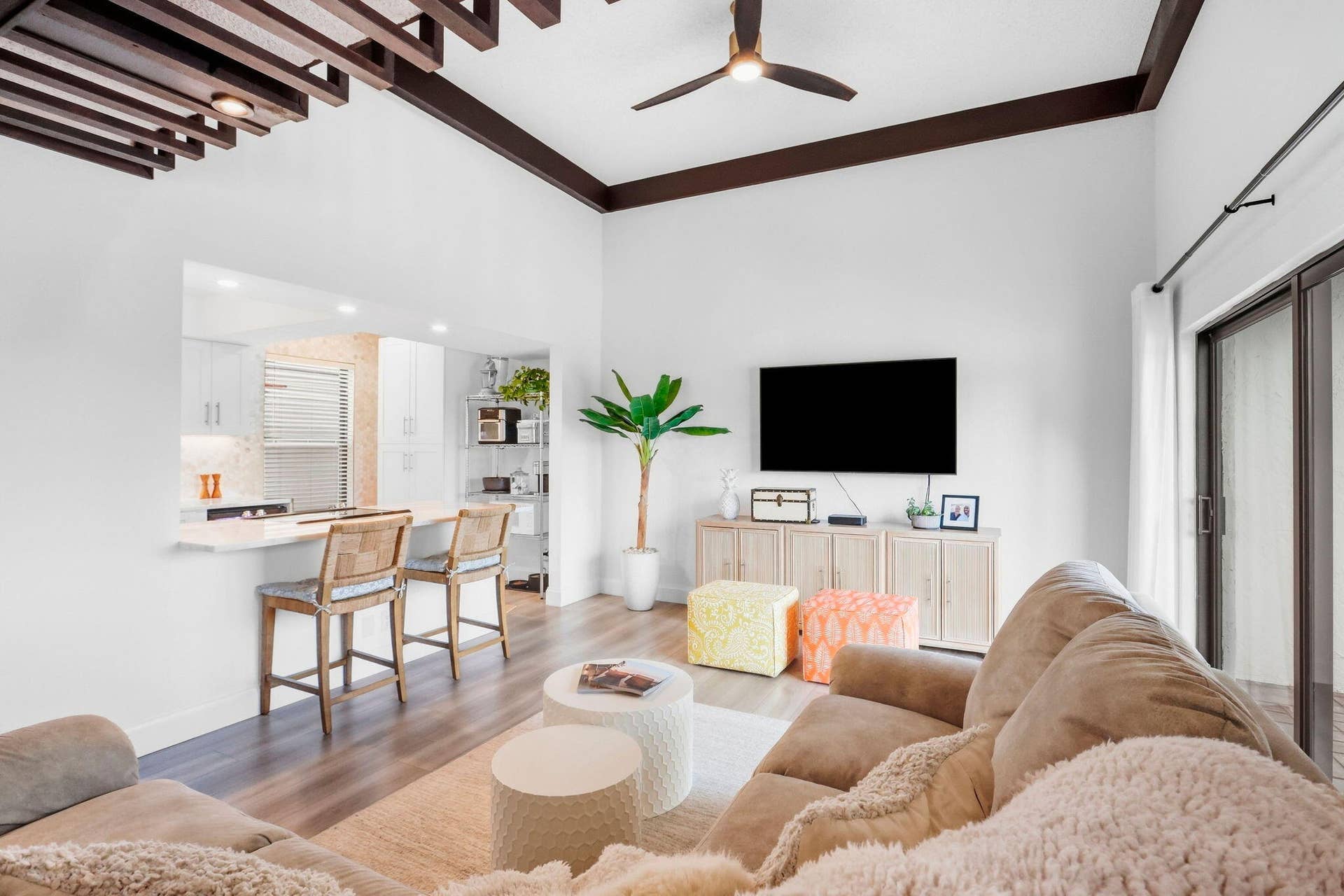 900 Greensward Lane, #209-G, Delray Beach, FL 33445 Vaulted ceiling with exposed wood beams, wood-finish flooring, sliding glass door, kitchen pass-through with breakfast bar, and recessed lighting