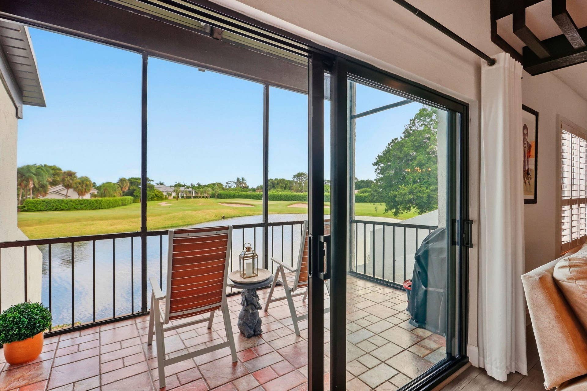 900 Greensward Lane, #209-G, Delray Beach, FL 33445 Screened-in patio with brick-patterned flooring, black metal railings, and sliding glass doors