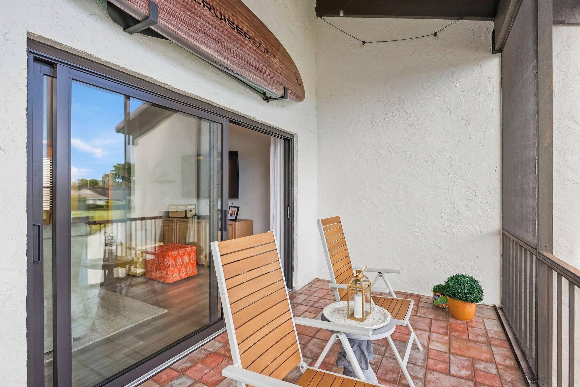 900 Greensward Lane, #209-G, Delray Beach, FL 33445 Patio featuring a brick-finish floor, white textured stucco walls, dark-framed sliding glass doors, and a screened enclosure