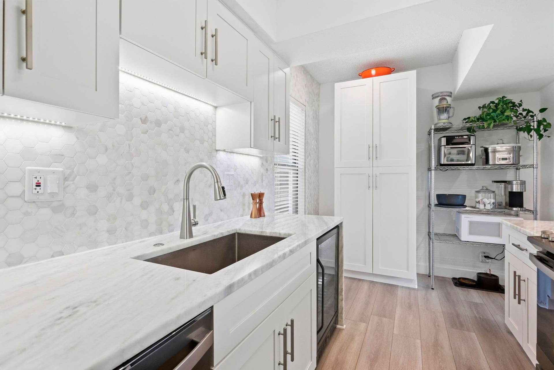 900 Greensward Lane, #209-G, Delray Beach, FL 33445 White shaker cabinetry with brushed nickel hardware, light-toned countertops, hexagonal tile backsplash, under-cabinet lighting, and wood-finish flooring