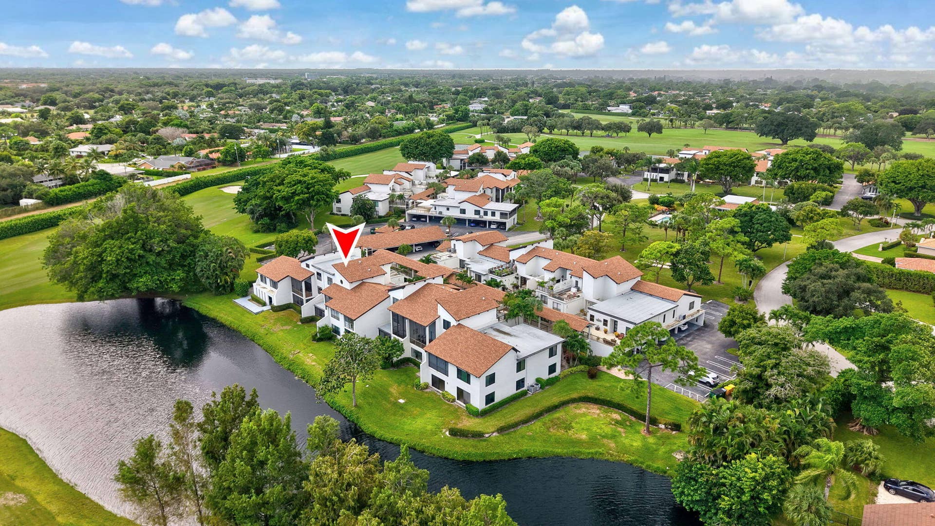 900 Greensward Lane, #209-G, Delray Beach, FL 33445 Waterfront property in a community setting, featuring terracotta-style roofing, surrounding green spaces, and mature landscaping