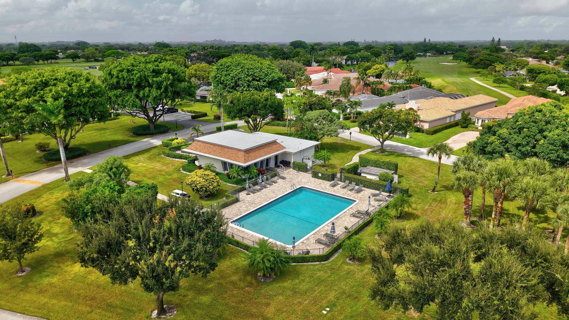 900 Greensward Lane, #209-G, Delray Beach, FL 33445 Community pool with surrounding lounge area, adjacent clubhouse, and mature landscaping