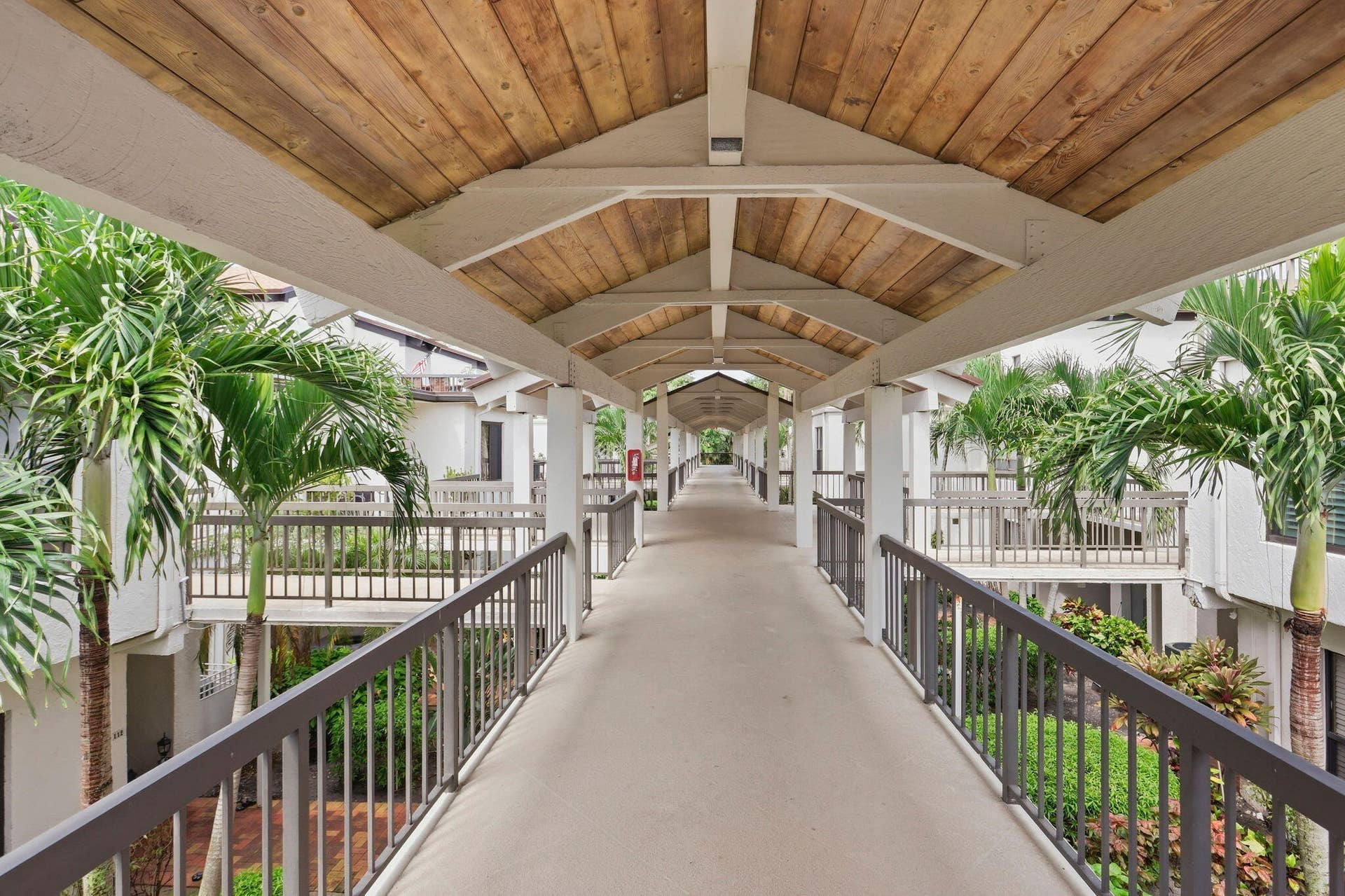 900 Greensward Lane, #209-G, Delray Beach, FL 33445 Covered walkway with a wood-finish ceiling, white beams, and dark railings