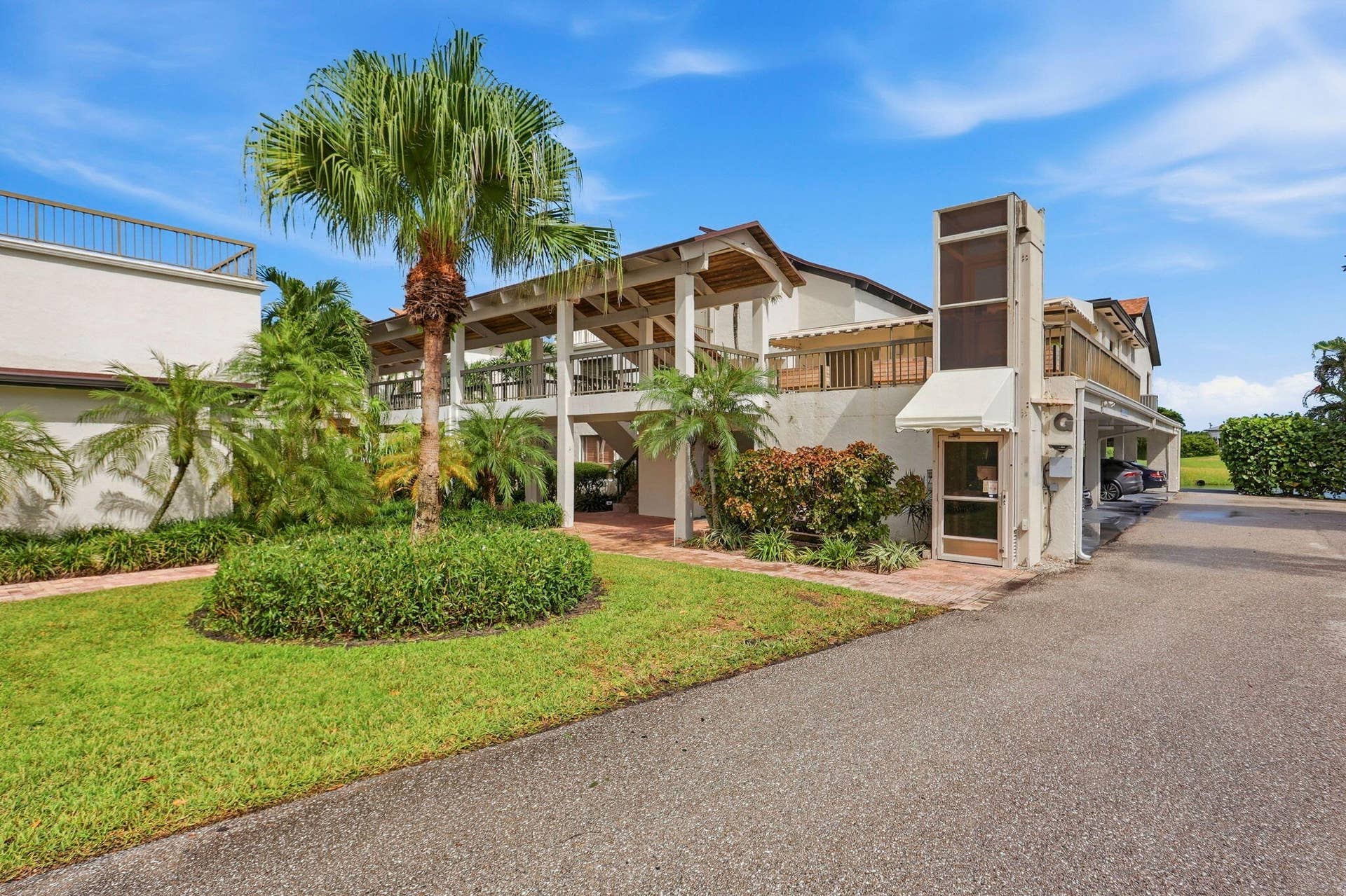 900 Greensward Lane, #209-G, Delray Beach, FL 33445 Exterior with multiple balconies, a covered walkway, and a built-in elevator structure