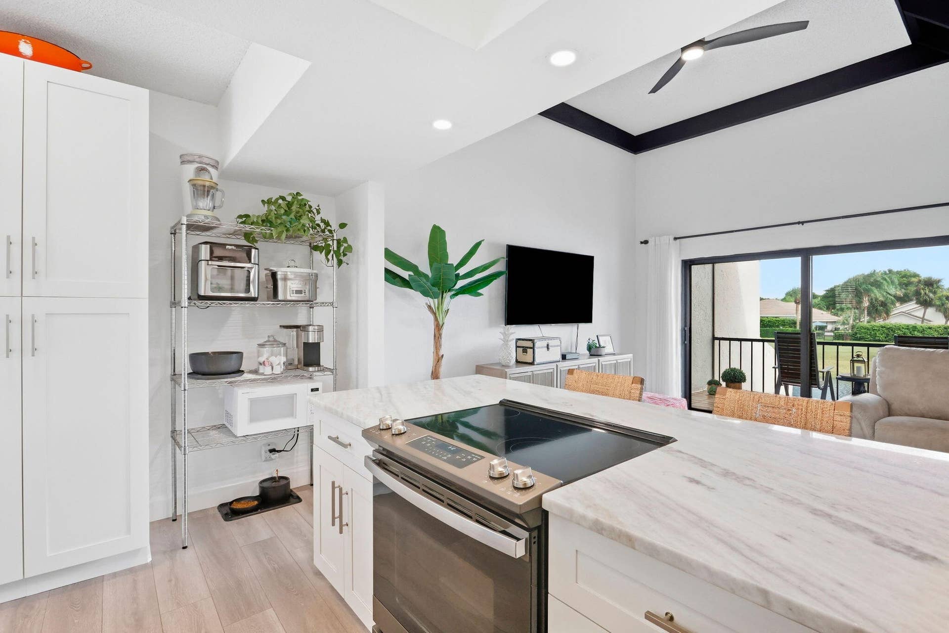 900 Greensward Lane, #209-G, Delray Beach, FL 33445 Kitchen island with a built-in electric cooktop, white cabinetry, wood-finish flooring, and a sliding glass door to an outdoor space