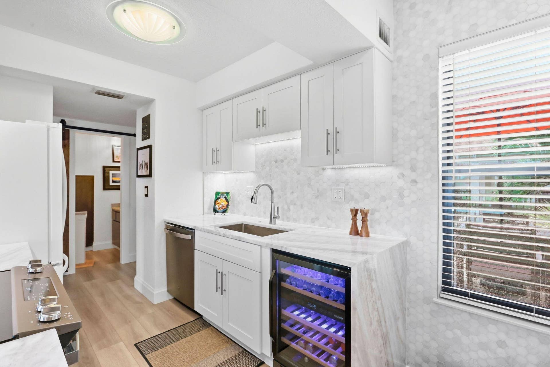 900 Greensward Lane, #209-G, Delray Beach, FL 33445 White cabinetry, integrated wine refrigerator, stainless steel appliances, marble-look countertop, and wood-finish flooring
