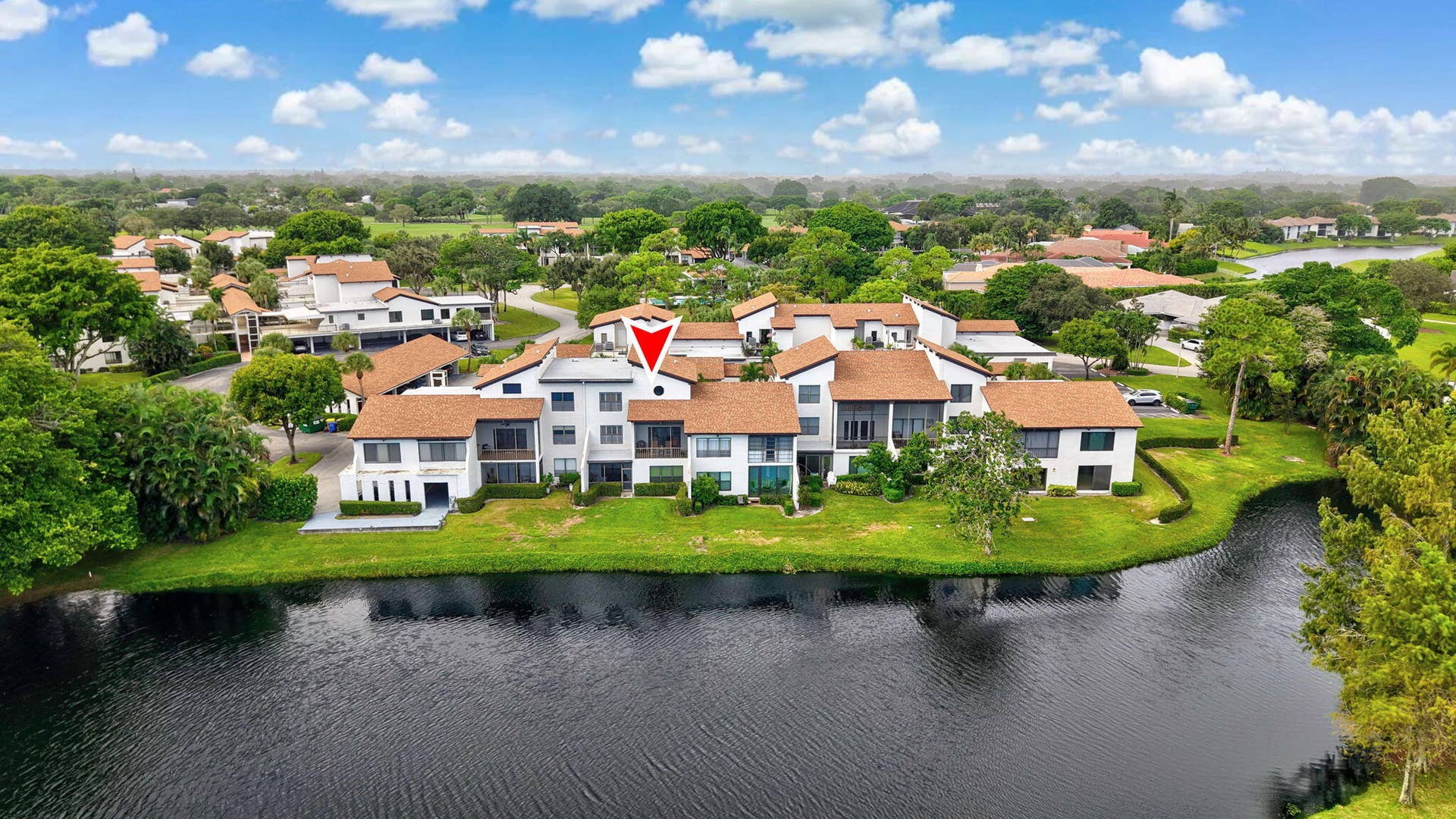 900 Greensward Lane, #209-G, Delray Beach, FL 33445 Building exterior featuring a light-toned stucco finish, brown shingle roofing, and multiple private balconies