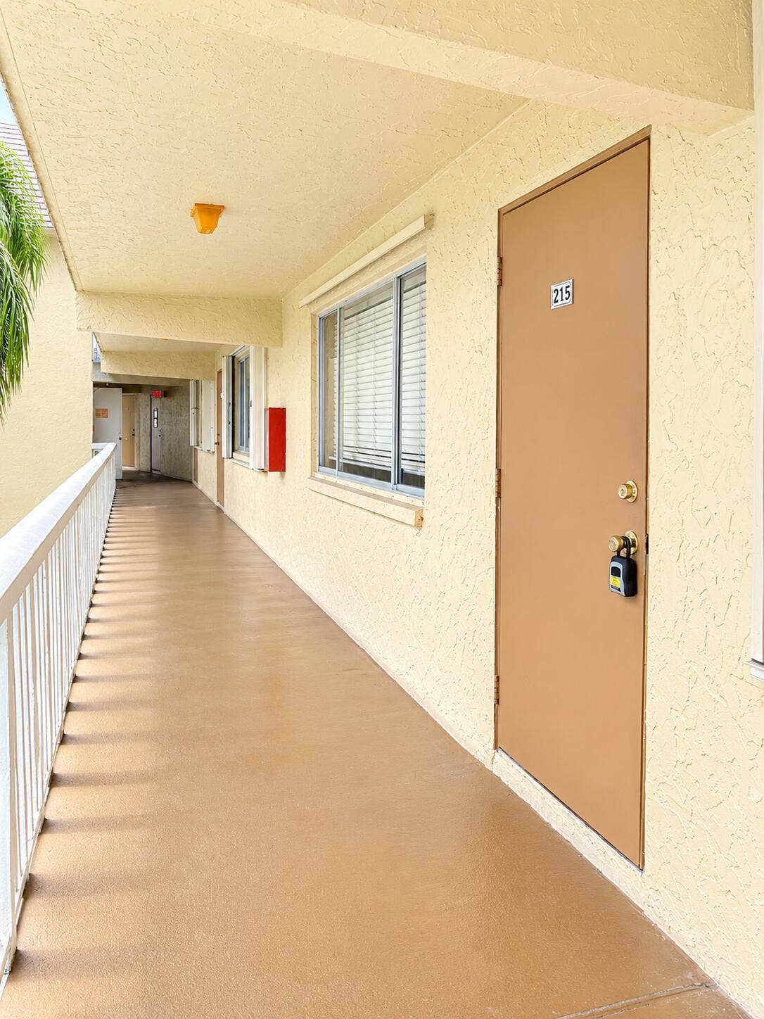 600 VILLAGE GREEN Court, #215, Palm Springs, Palm Springs, FL 33461 Sunlit Apartment Corridor with Door 215