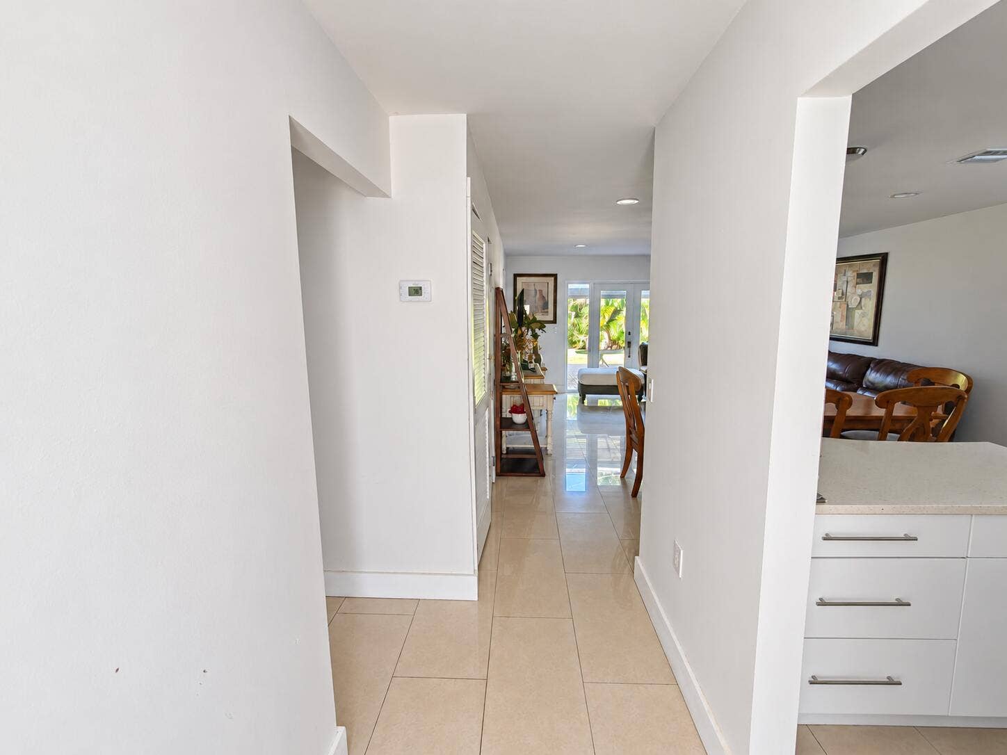 Tile flooring throughout, recessed lighting, and white cabinetry with contemporary hardware