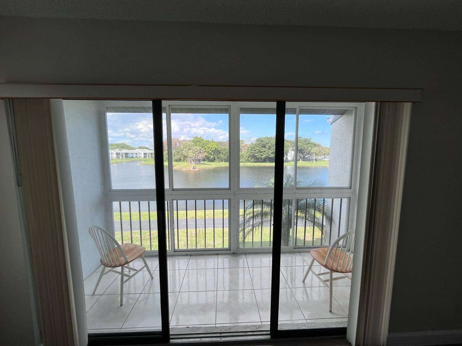 1002 Green Pine Boulevard, #F2, West Palm Beach, FL 33409 Sliding glass doors opening to a private balcony with tiled flooring and a metal railing