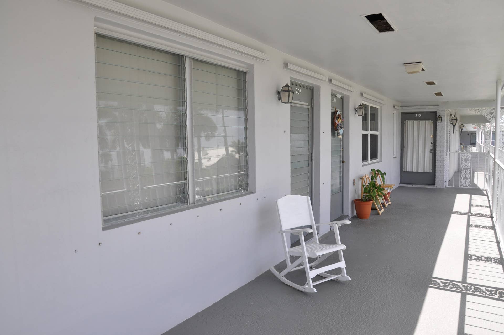630 Layne Boulevard, #208, Hallandale Beach, Hallandale Beach, FL 33009 Covered outdoor walkway featuring a textured concrete surface, white painted walls, and security doors