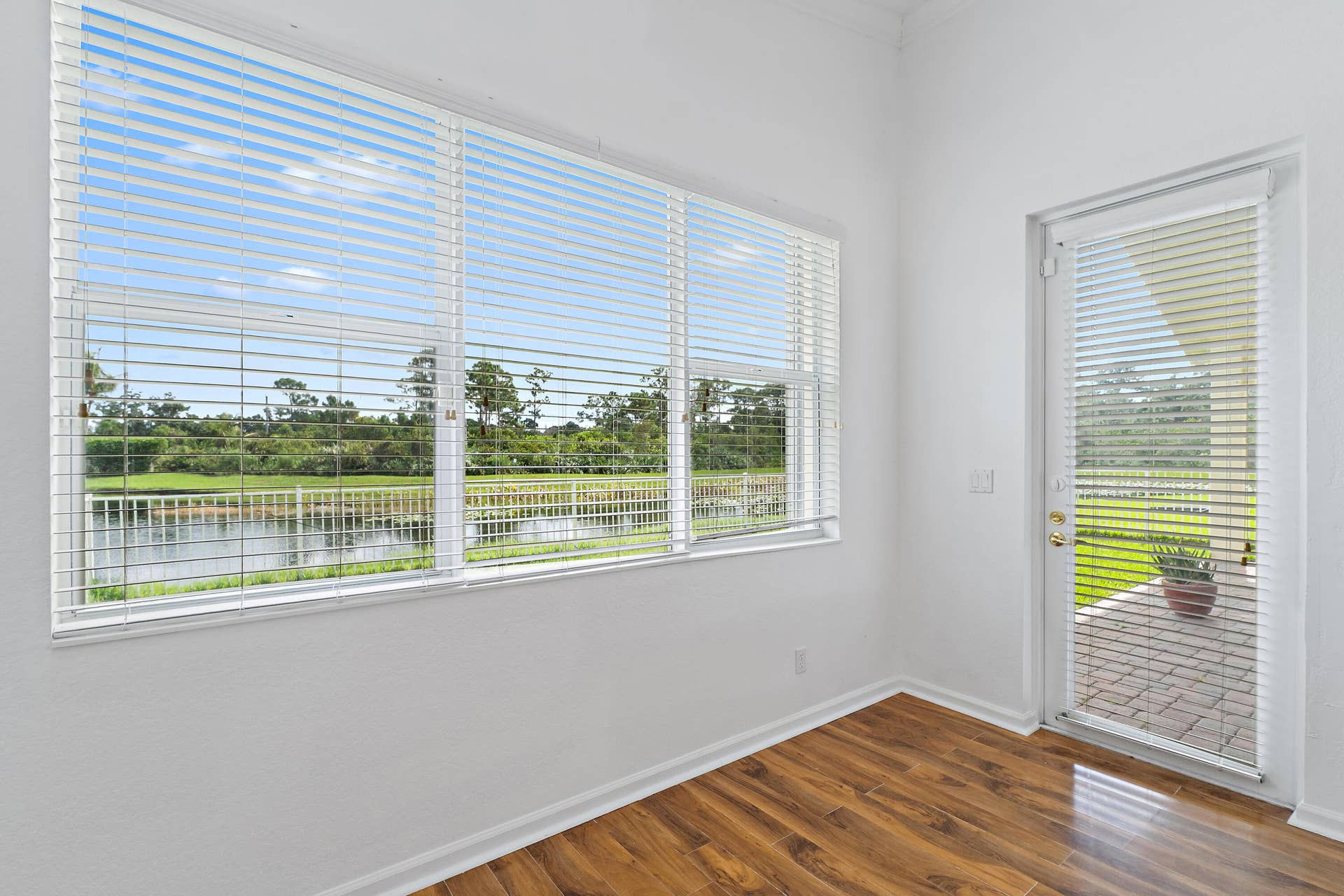 5183 SE Graham Drive, Stuart, FL 34997 The primary bedroom is a peaceful retreat, with a wide window framing views of the pond and preserve. Its private door opens to the screened lanai, perfect for morning coffee or a quiet evening outside. Wood-look floors and plenty of natural light make it bright, calm, and inviting.